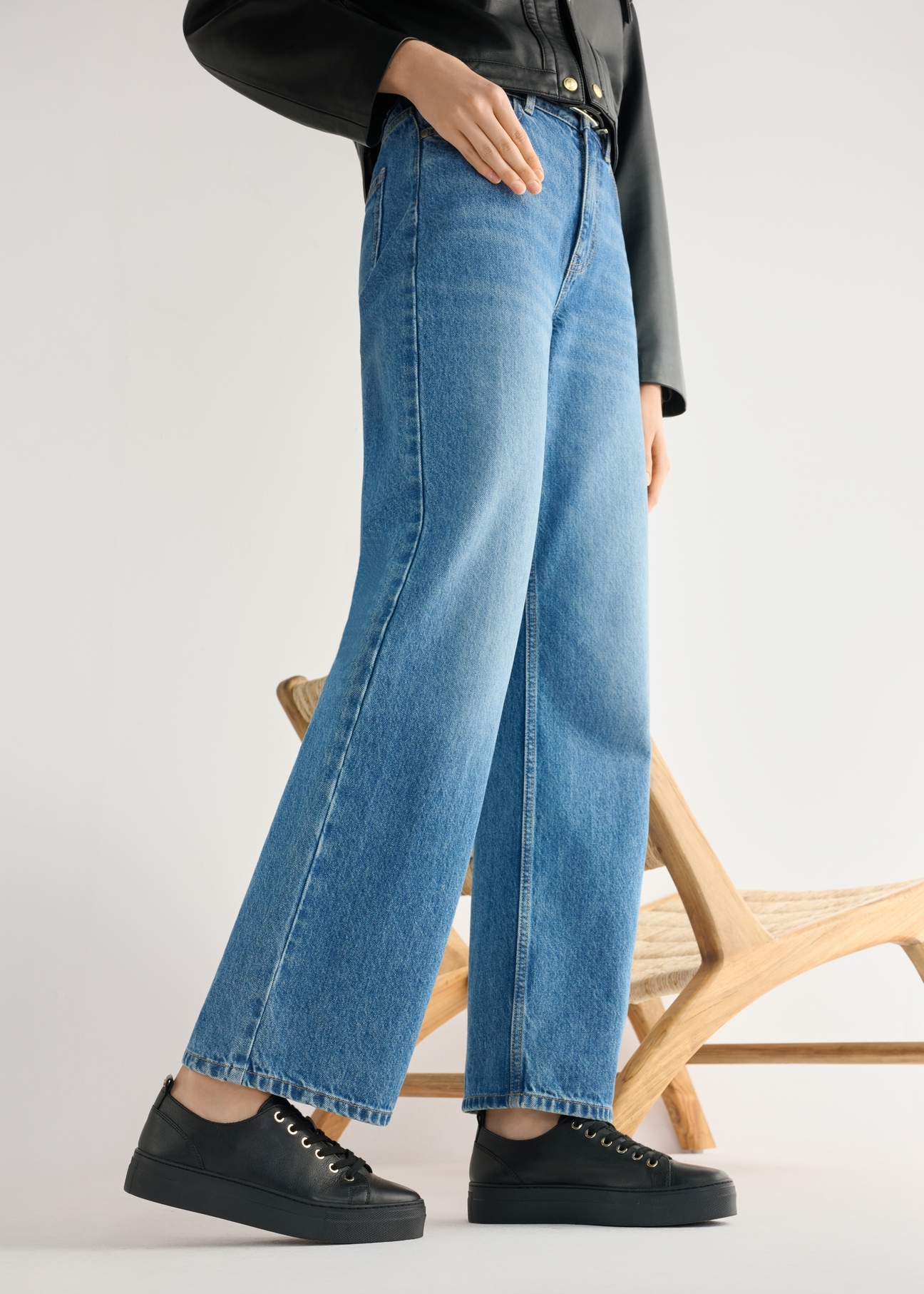 Wysokie czarne skórzane tenisówki damskie BUTYD-1062-99(W26) - widok produktu z boku, na modelce, na jasnym tle. Widoczna sylwetka do kolan. 