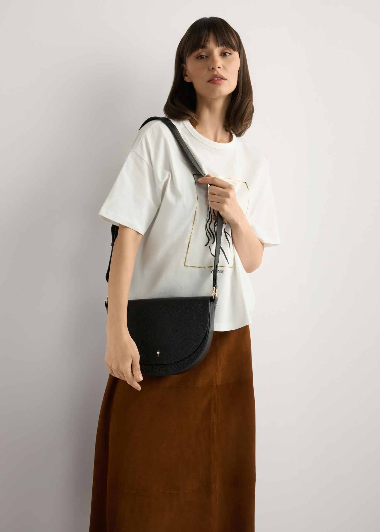 Czarna skórzana torebka damska TORES-0895D-99(Z25), widok produktu na ramieniu modelki. Widoczna połowa sylwetki.