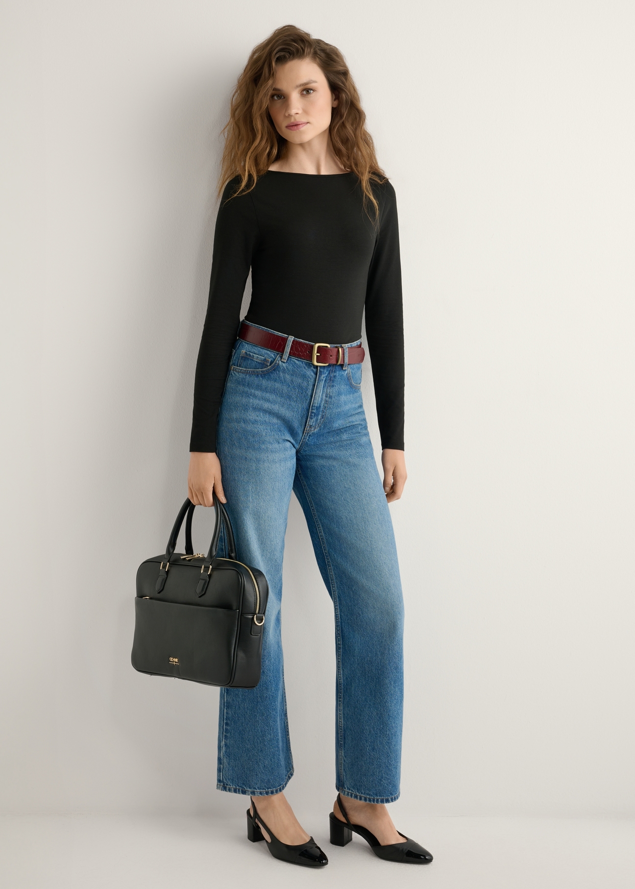 Czarna torba na laptopa damska TOREC-1209-99(W26), widok produktu w dłoni modelki. Widoczna cała sylwetka.