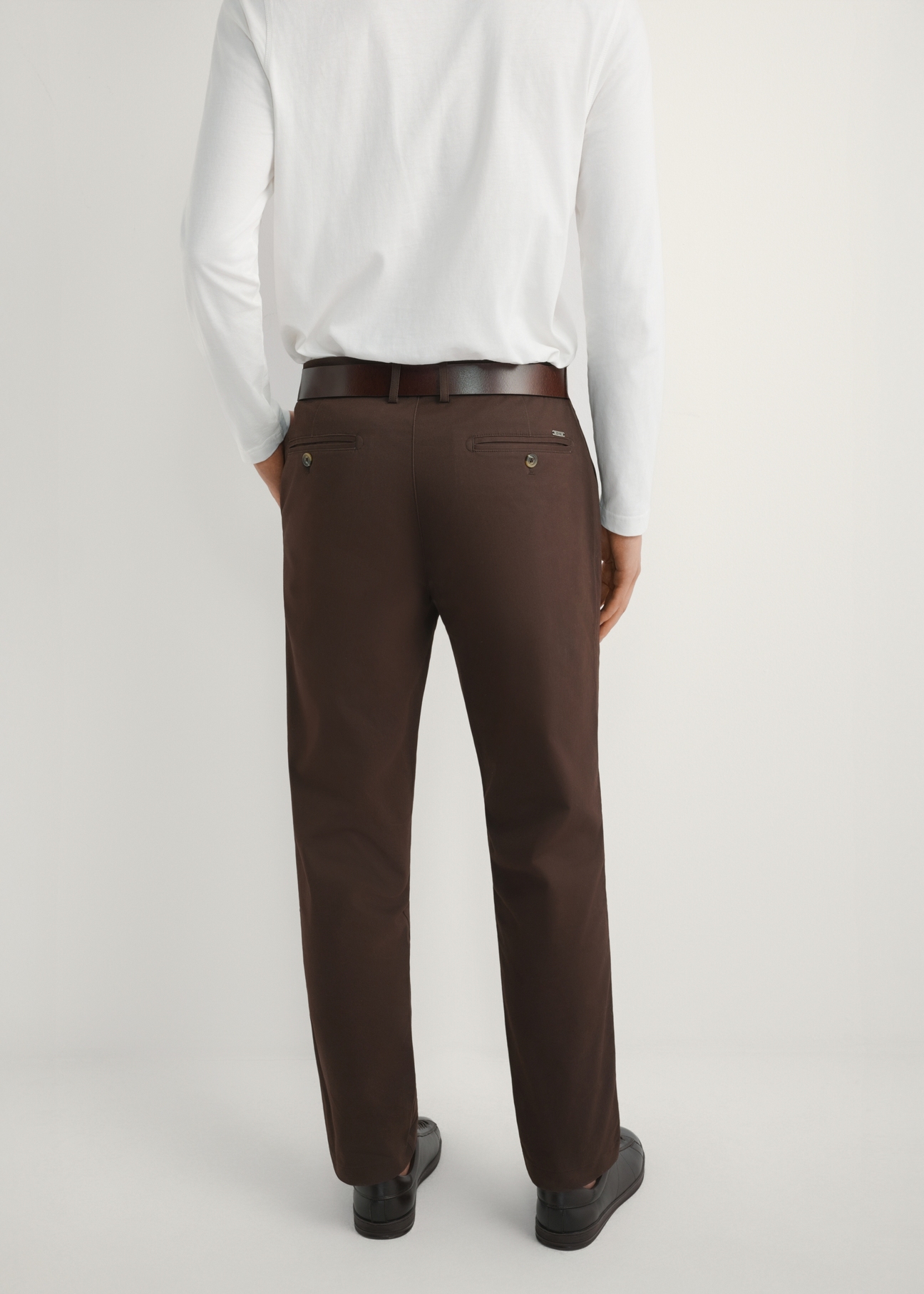 Brązowe spodnie męskie SPOMT-0121-1I(W26) - widok produktu z tyłu na modelu, na jasnym tle. Widoczna połowa sylwetki. 