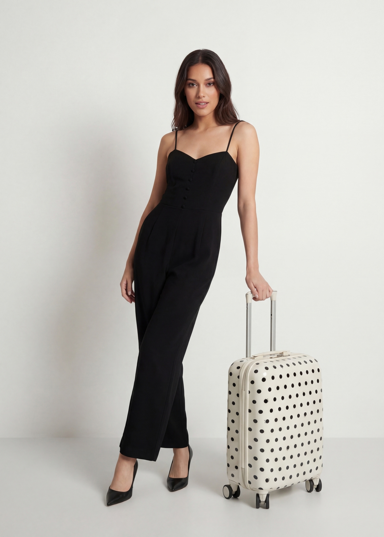 Mała walizka w kropki na kółkach WALAB-0074-0P-19(W26), widok produktu skosem obok sylwetki modelki.