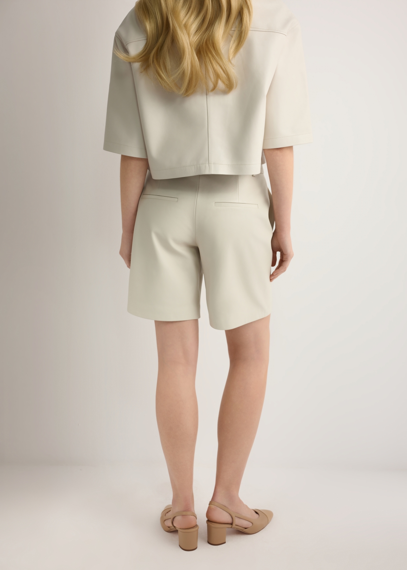 Skórzane kremowe szorty damskie SPODS-0047-0B(W26), widok produktu z tyłu na modelce. Widoczna połowa sylwetki.