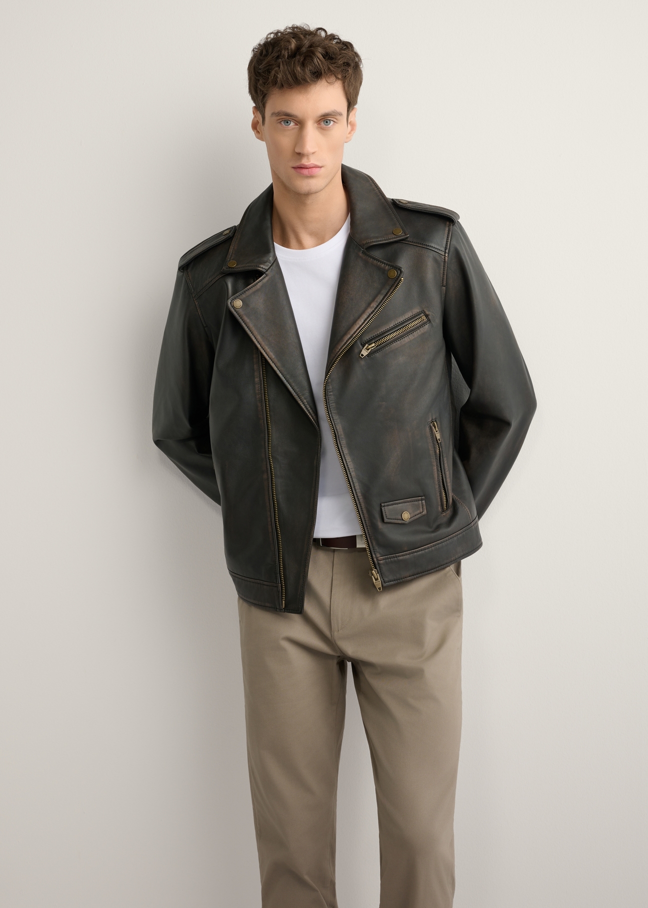 Skórzana kurtka męska ramoneska KURMS-0395-99(W26) - widok produktu z przodu, na modelu, na jasnym tle. Widoczna cała sylwetka. 
