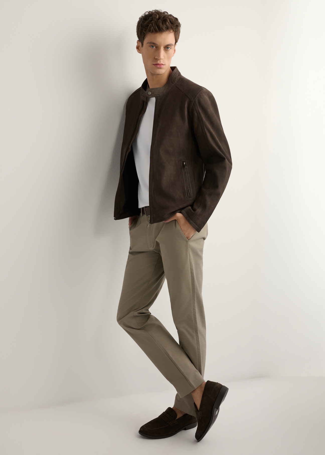 Brązowa zamszowa kurtka męska KURMS-0396-1I(W26) - widok produktu z boku, na modelu, na jasnym tle. Widoczna cała sylwetka. 