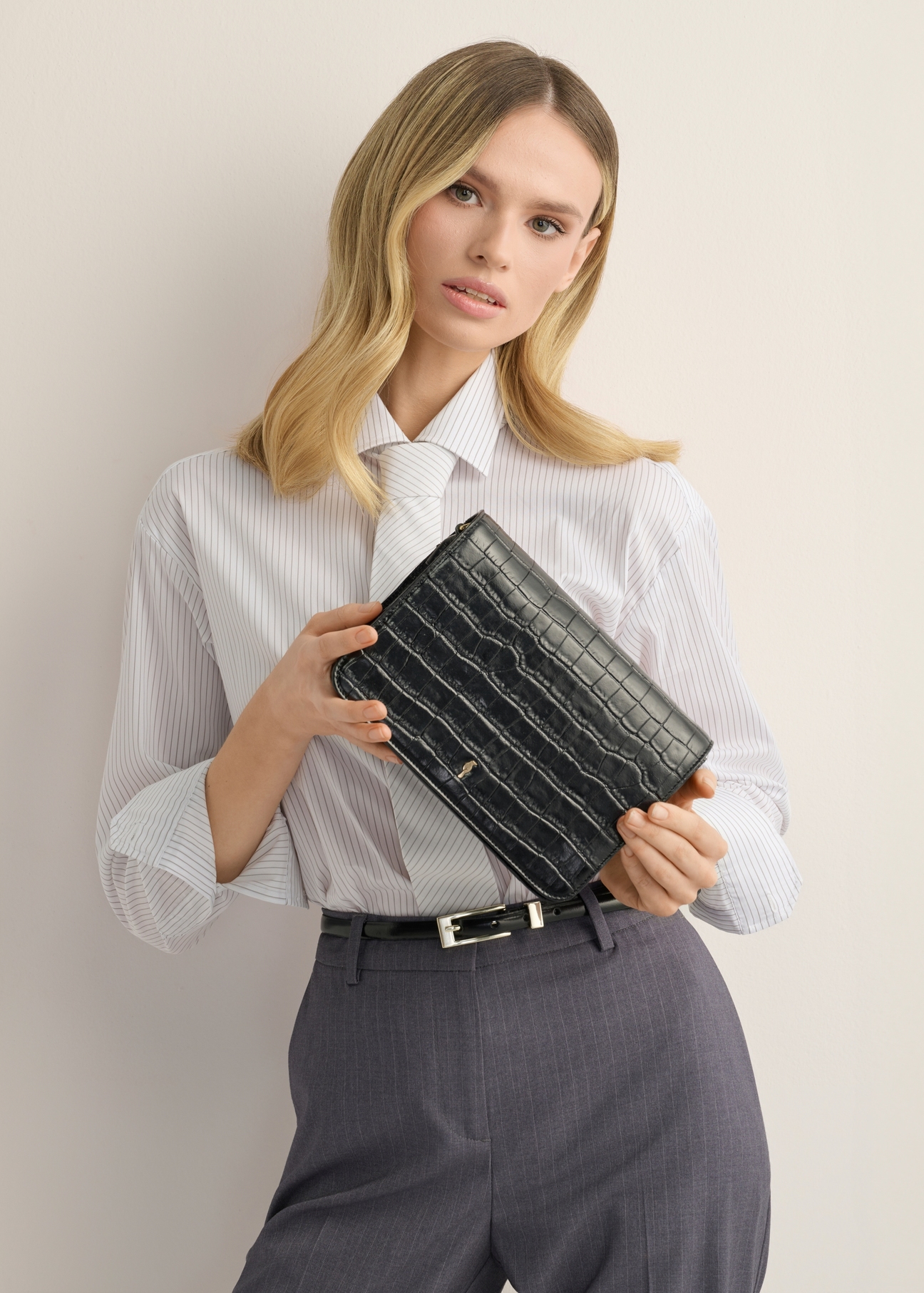 Skórzana czarna torebka damska croco TORES-1324-9G(Z26), widok produktu w dłoniach modelki. Widoczna połowa sylwetki.