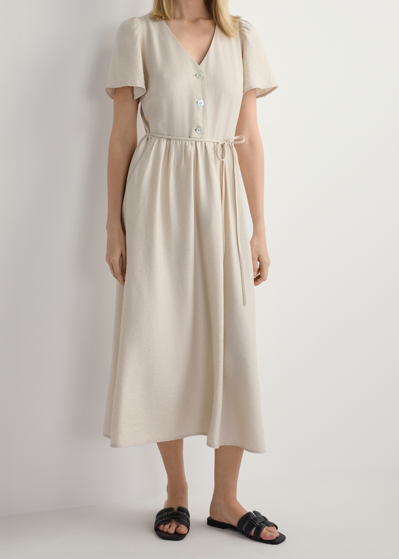 Czarne skórzane klapki damskie z plecionką BUTYD-1225-99(W26), widok produktu z przodu na stopach modelki, na białym tle. Widoczna połowa sylwetki.