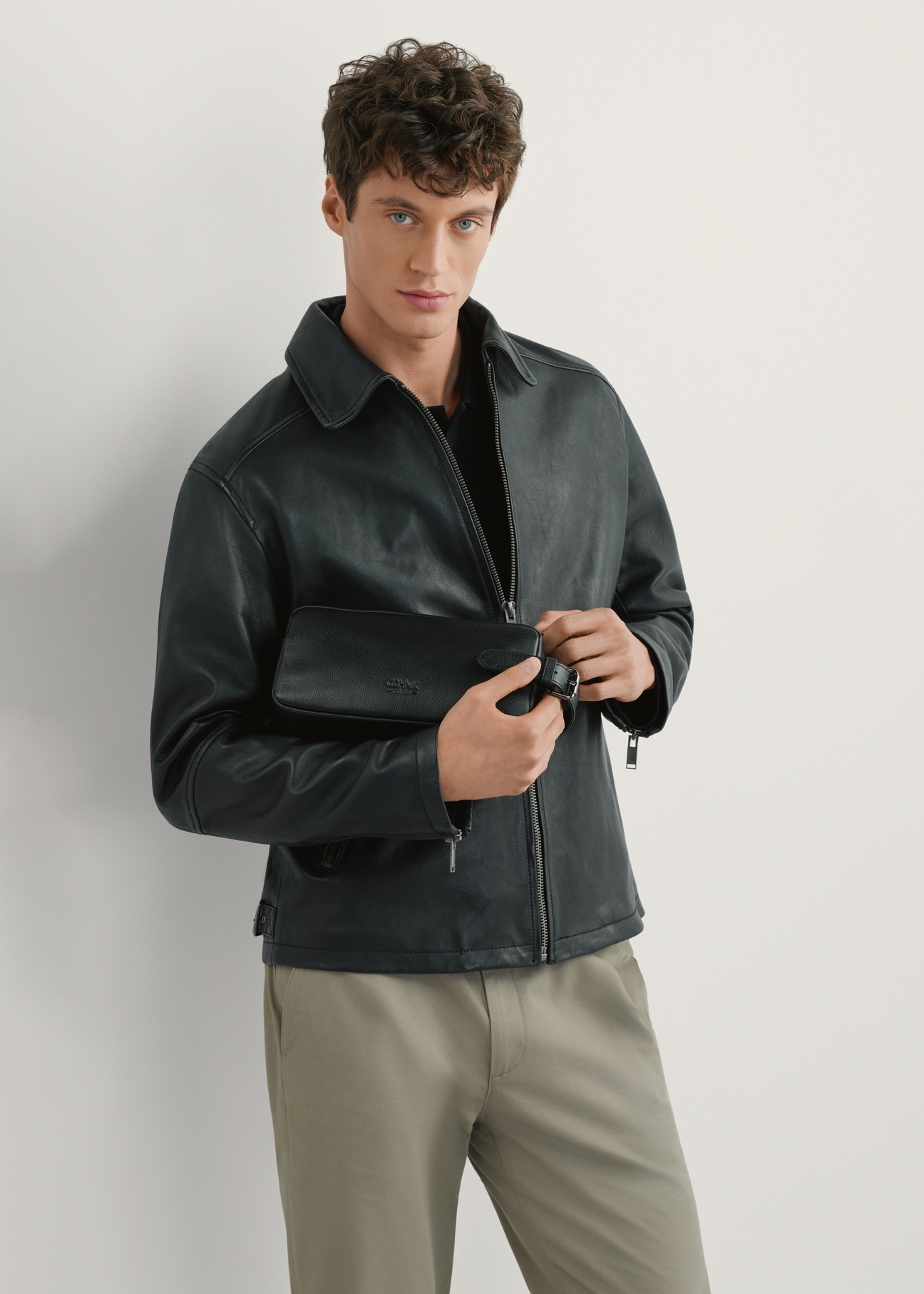 Czarna skórzana kosmetyczka męska TORMS-0412R-9I(W26), widok produktu od przodu na modelu, widoczna połowa sylwetki.