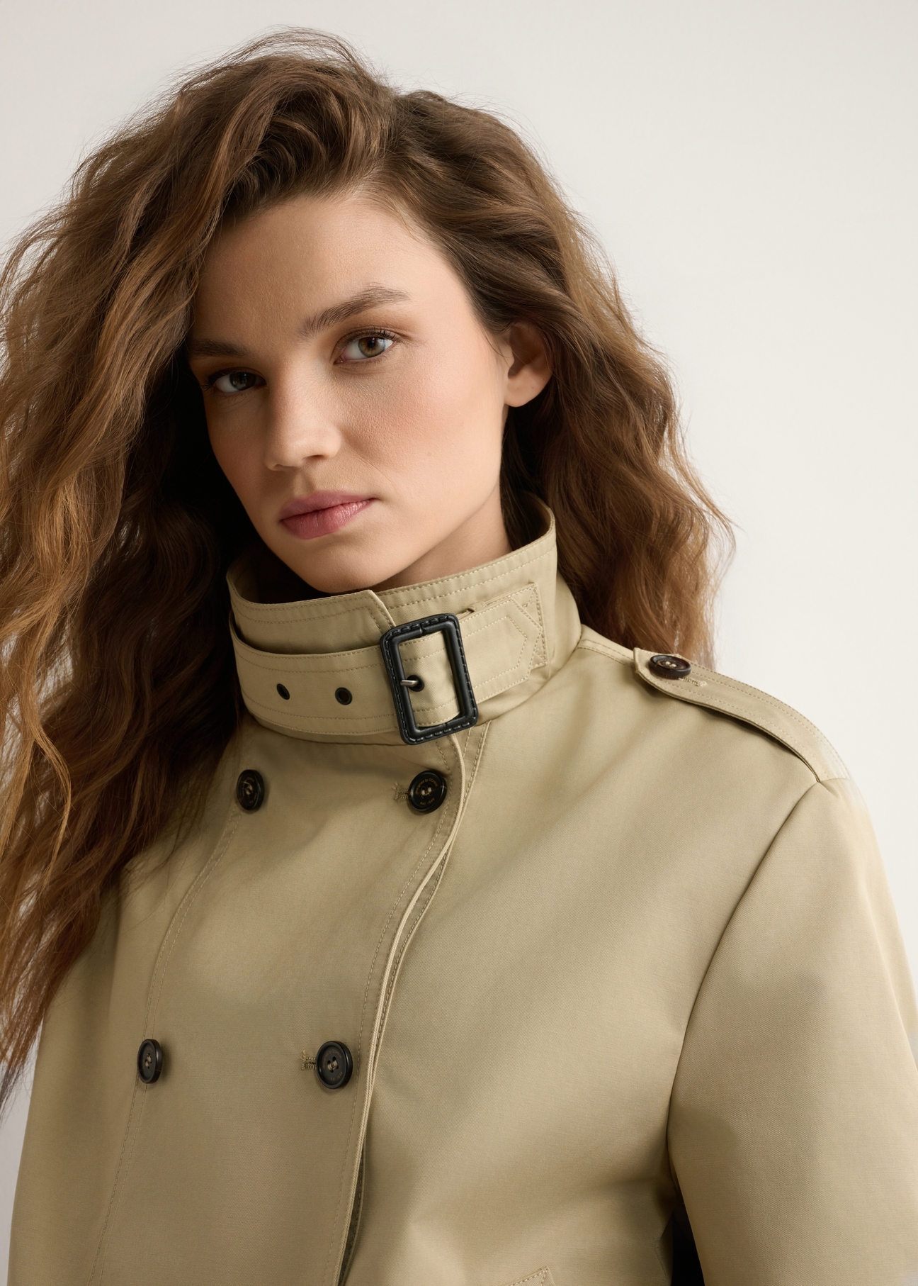 Beżowa krótka kurtka damska KURDT-0657-1B(W26) - widok produktu z przodu na modelce, na jasnym tle. Widoczne zbliżenie.