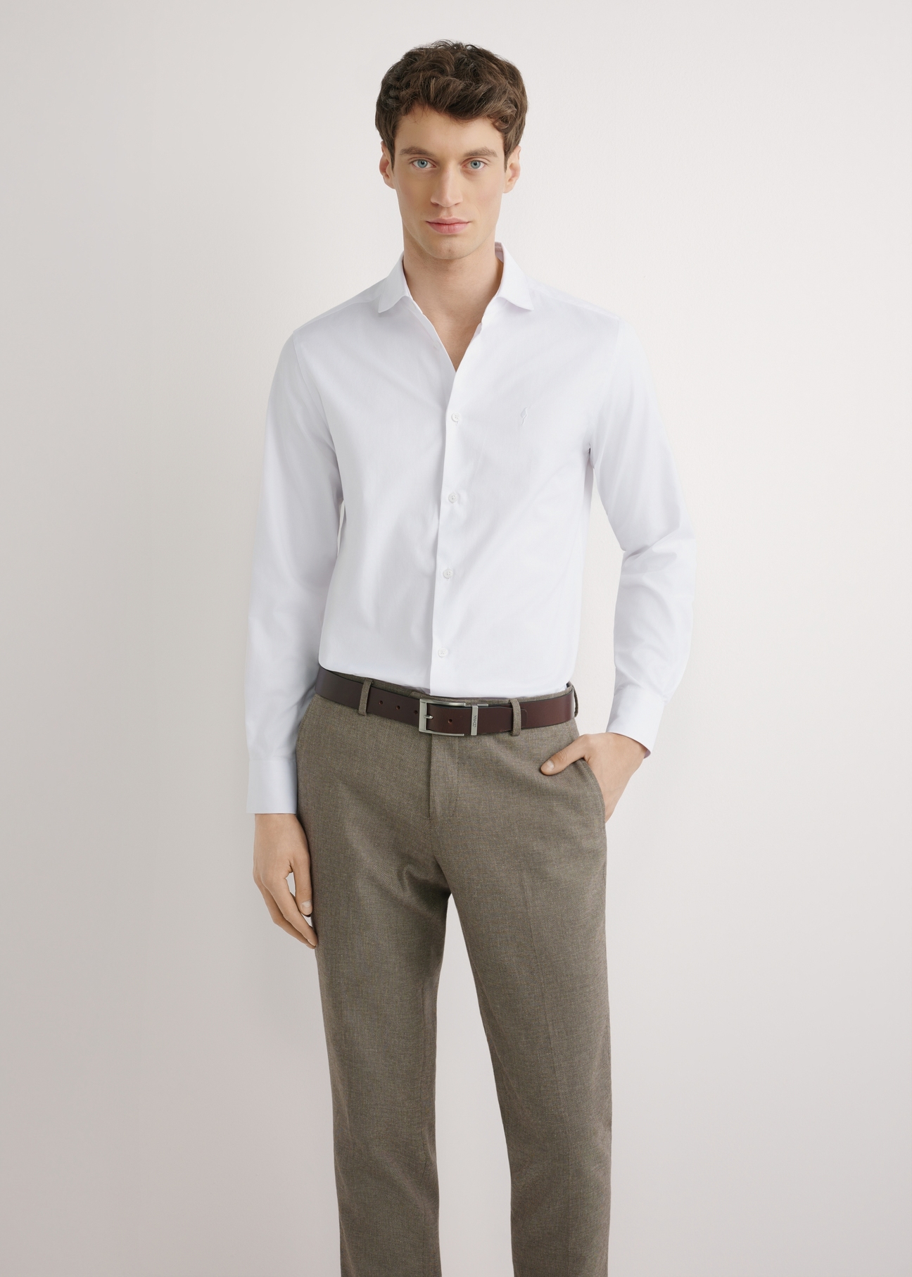 Biała koszula męska z bawełny KOSMT-0358-0A(W26) - widok produktu z przodu, na modelu, na jasnym tle. Widoczna sylwetka do połowy.