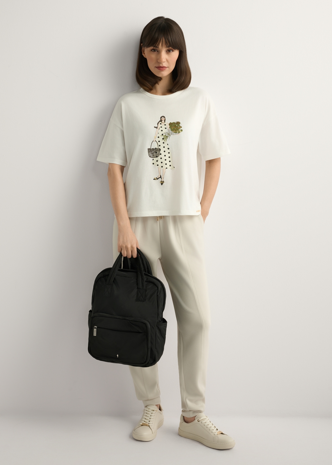 Czarny nylonowy plecak damski TOREN-0341-99(W26), widok produktu w dłoni modelki. Widoczna cała sylwetka.