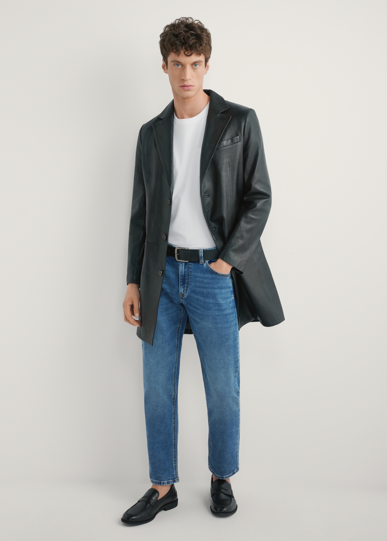 Czarny skórzany płaszcz męski KURMS-0388-99(W26) - widok produktu z przodu na modelu, na jasnym tle. Widoczna cała sylwetka.