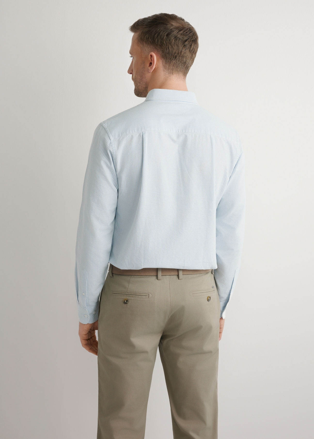 Bawełniana błękitna koszula męska w paski KOSMT-0354-7B(W26), widok produktu z tyłu na modelu. Widoczna połowa sylwetki.