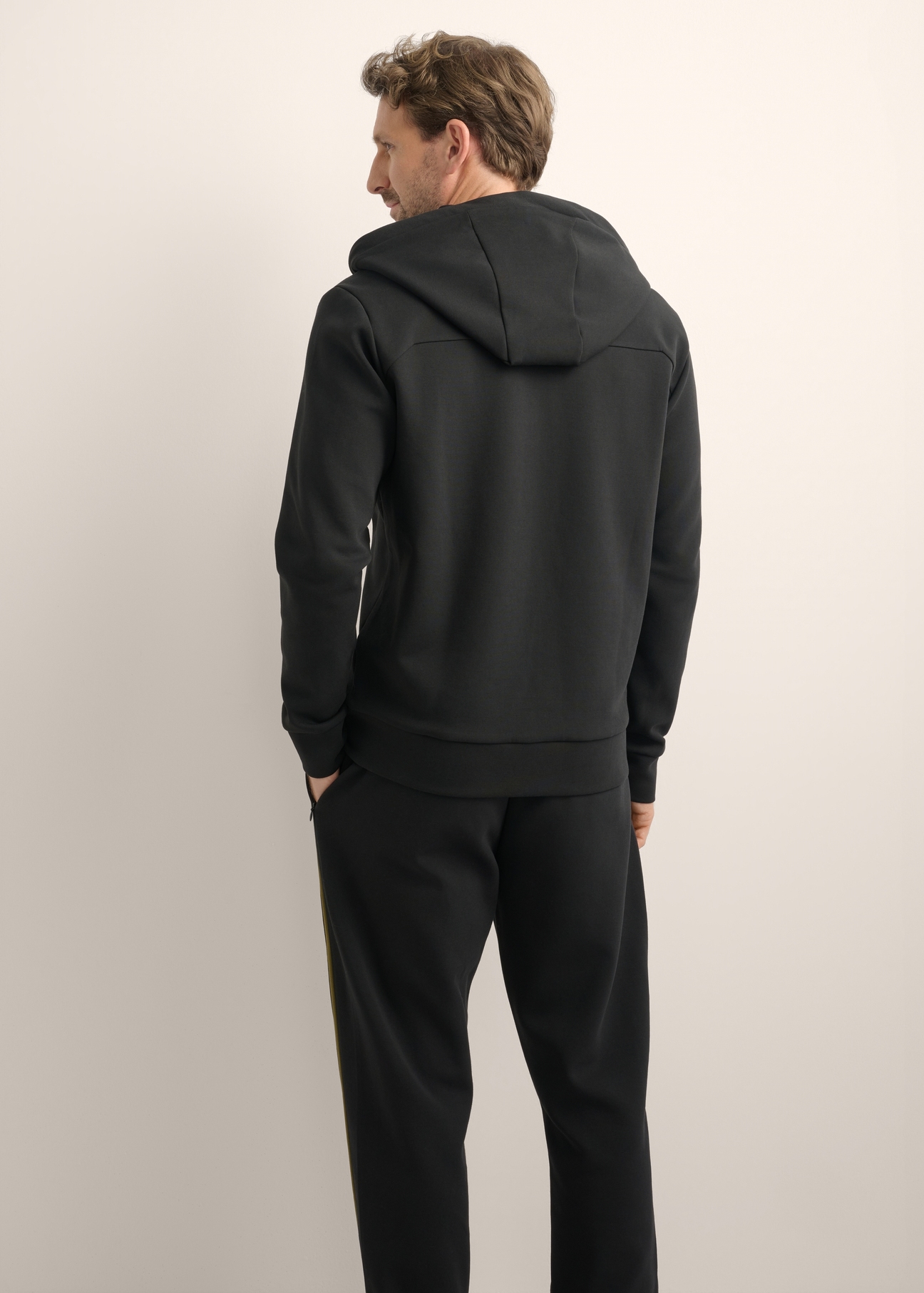 Rozpinana czarna bluza męska z kapturem BLZMT-0083-99(Z26), widok produktu od tyłu na modelu. Widoczna połowa sylwetki.
