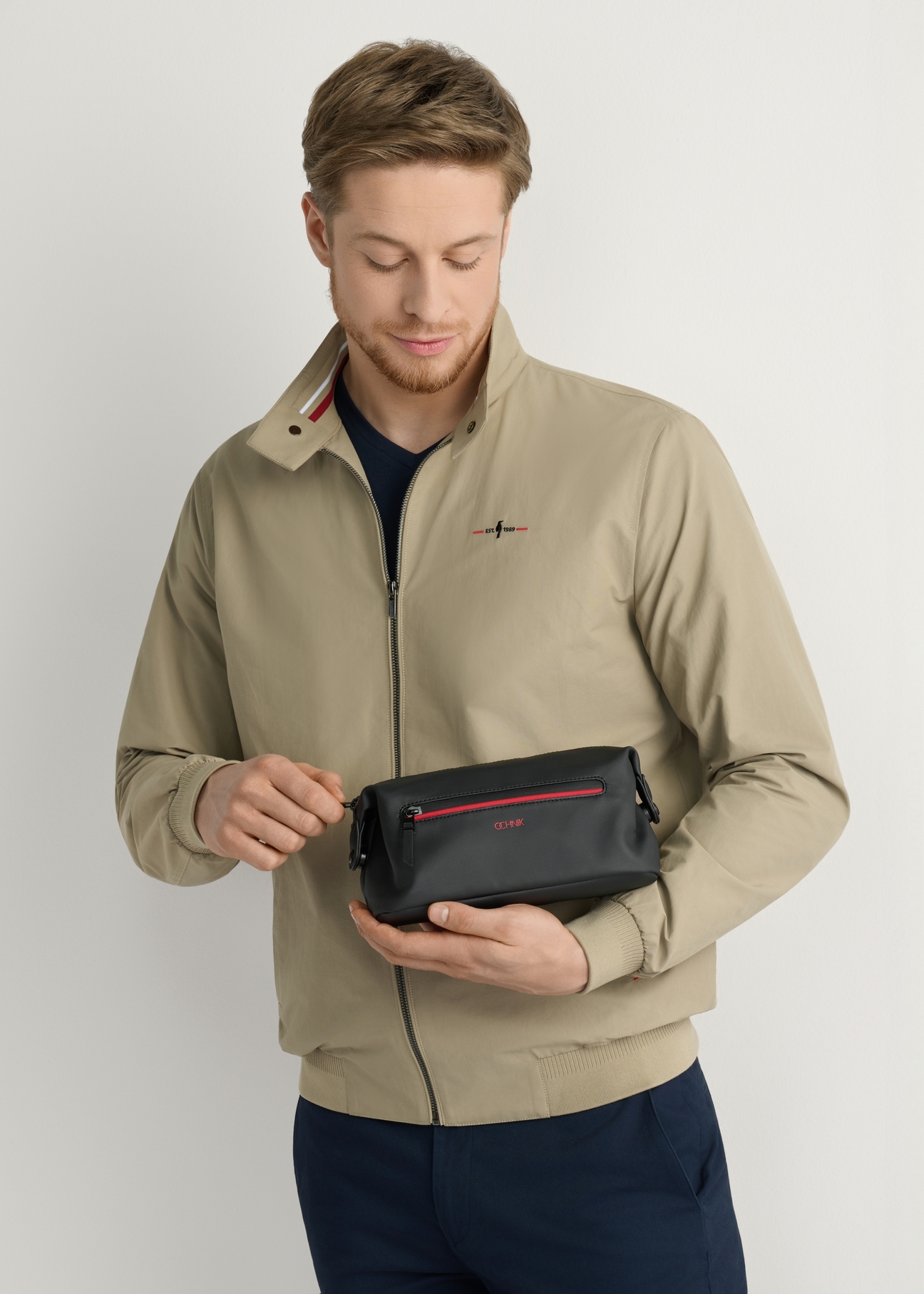 Czarna kosmetyczka męska TORMN-0397-9J(W26), widok produktu w dłoni modela, na jasnym tle.