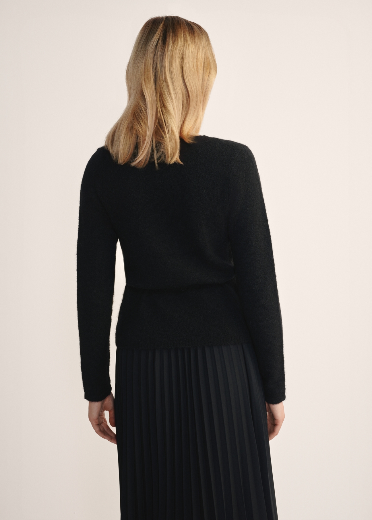 Czarny sweter damski z wiązaniem SWEDT-0234-99(Z25), widok produktu z tyłu na modelce. Widoczna połowa sylwetki.