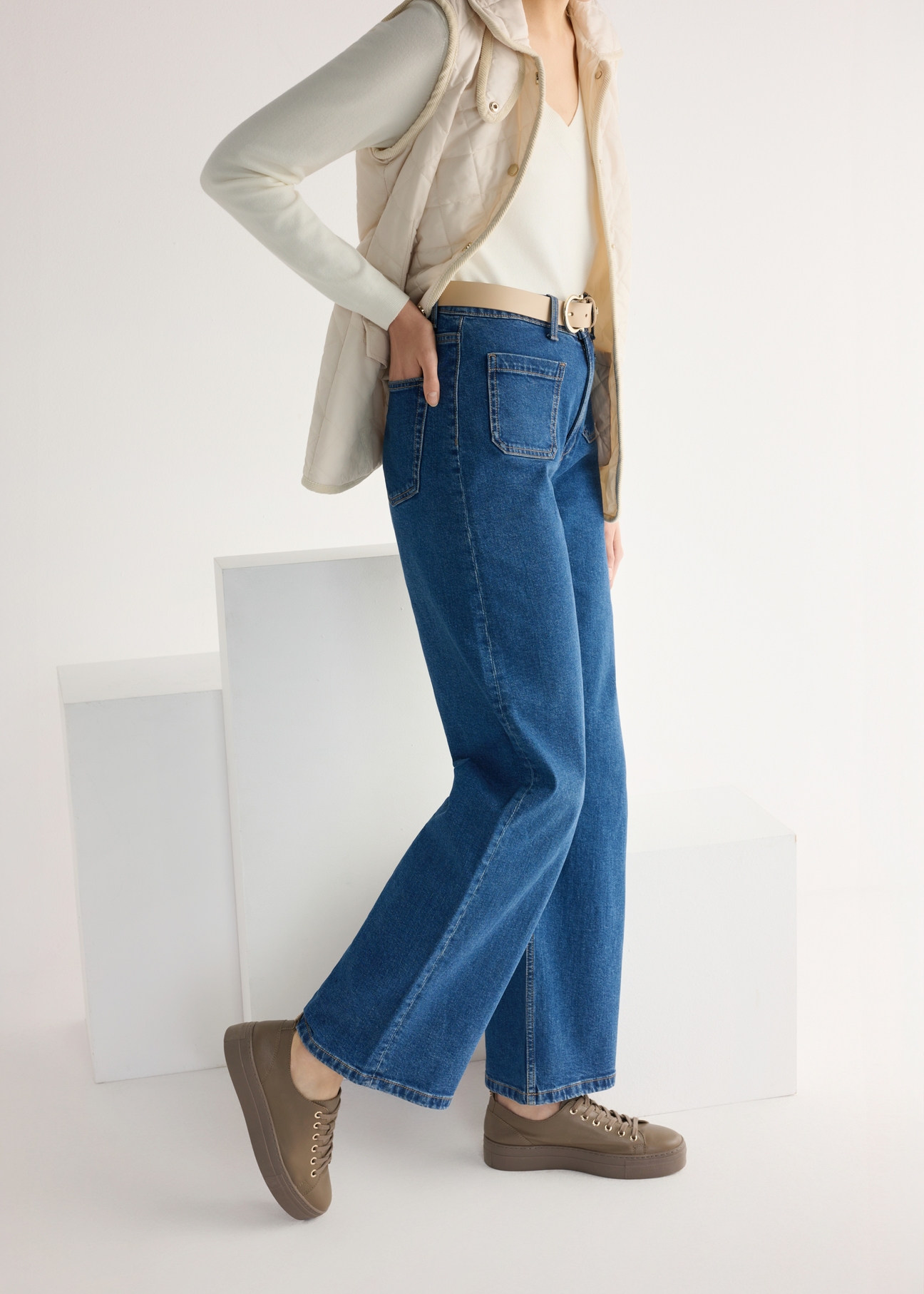 Skórzane tenisówki damskie w kolorze chłodnego beżu BUTYD-1062-1K(W26), widok produktu od boku na modelce, widoczna połowa sylwetki.