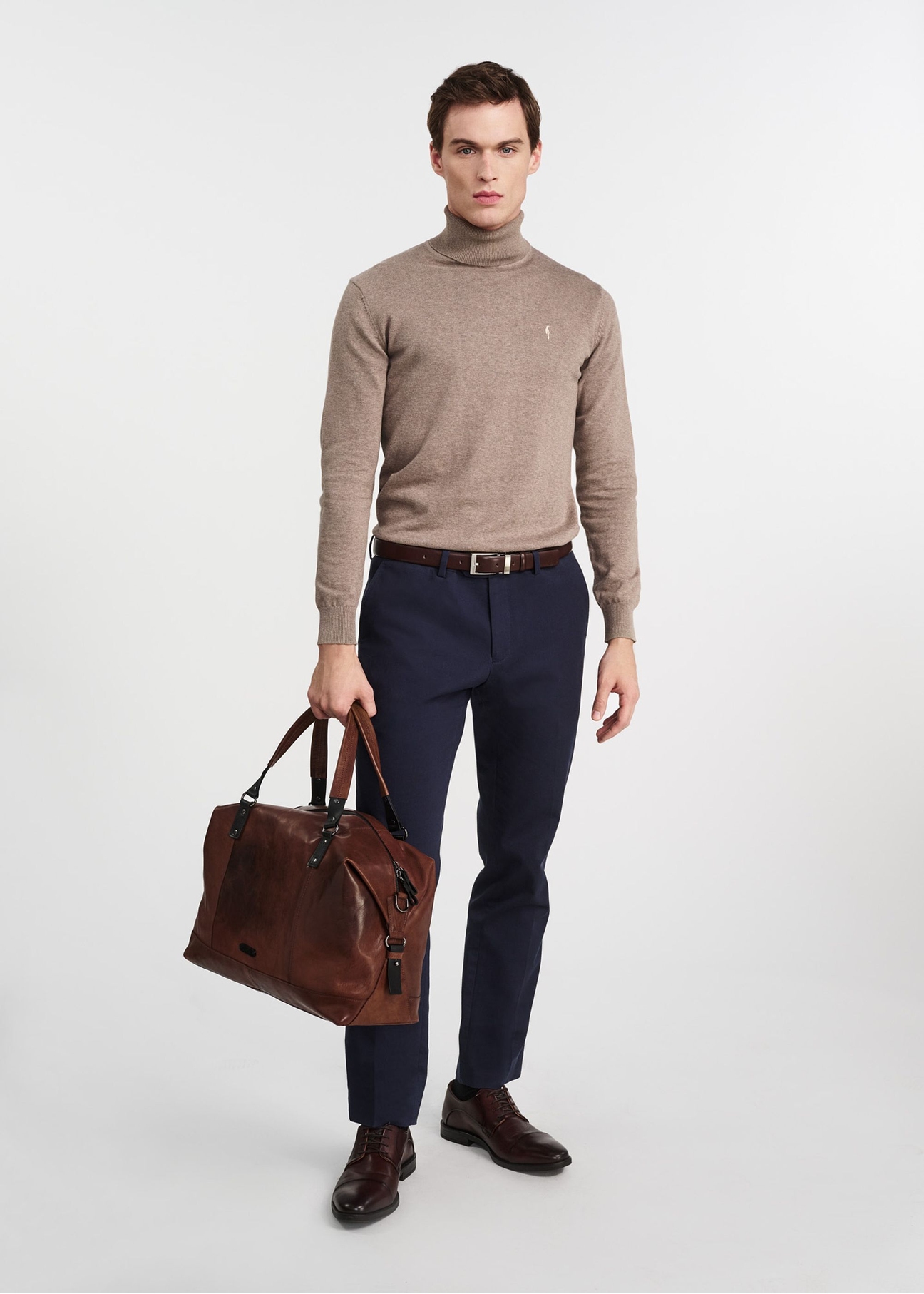 Brązowa skórzana duża torba męska TORMS-0103-1H(W26), widok produktu w dłoni modela, na jasnym tle.