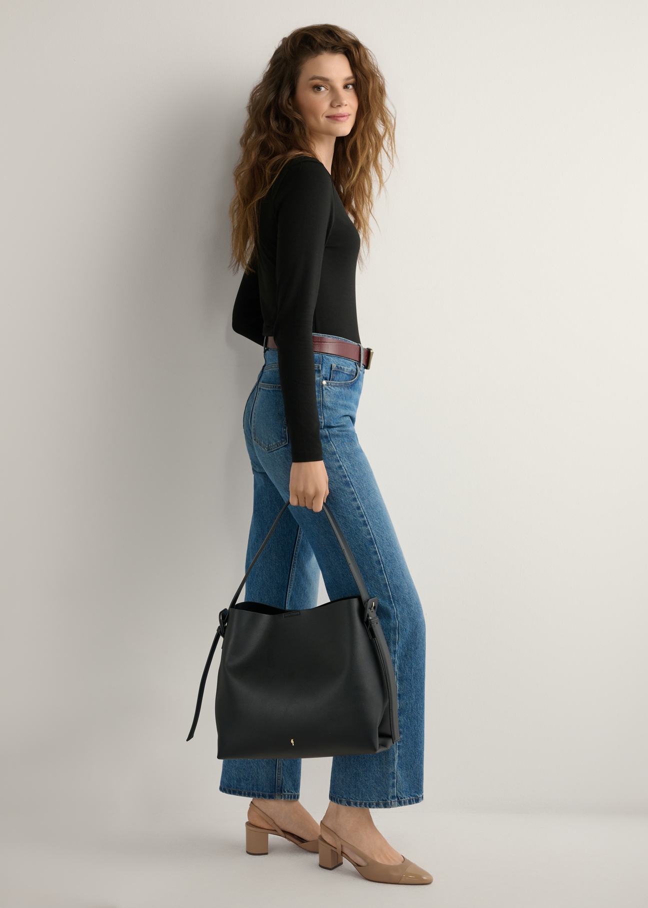 Czarna shopperka z imitacji skóry TOREC-0903-99(W24), widok produktu od przodu na modelce, widoczna cała sylwetka.