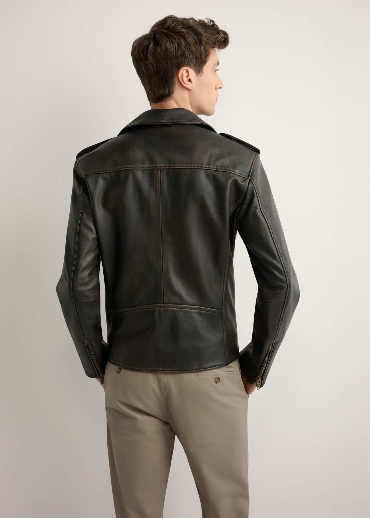 Skórzana kurtka męska ramoneska KURMS-0395-99(W26) - widok produktu z tyłu, na modelu, na jasnym tle. Widoczna cała sylwetka.