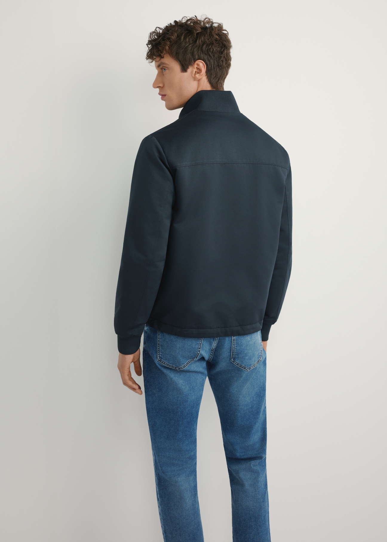 Granatowa przejściowa kurtka męska KURMT-0404-7D(W26), widok produktu z tyłu na modelu. Widoczna połowa sylwetki.