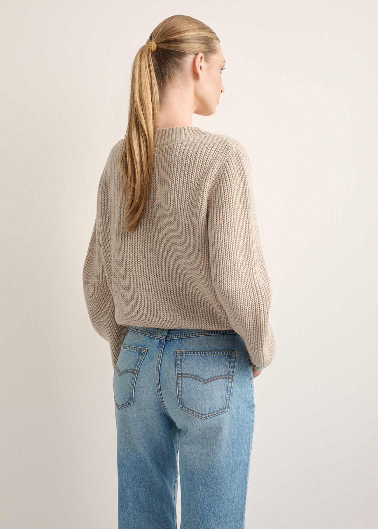 Sweter damski w kolorze chłodnego beżu SWEDT-0162-1J(Z26), widok produktu z tyłu na modelce. Widoczna połowa sylwetki. 