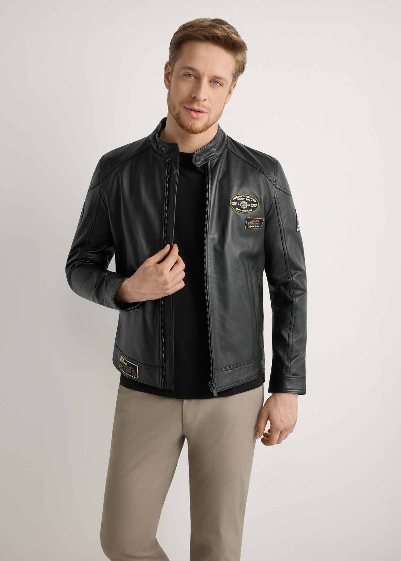 Skórzana czarna kurtka męska KURMS-0301A-99(W26) - widok produktu z przodu, na modelu, na jasnym tle. Widoczna połowa sylwetki. 