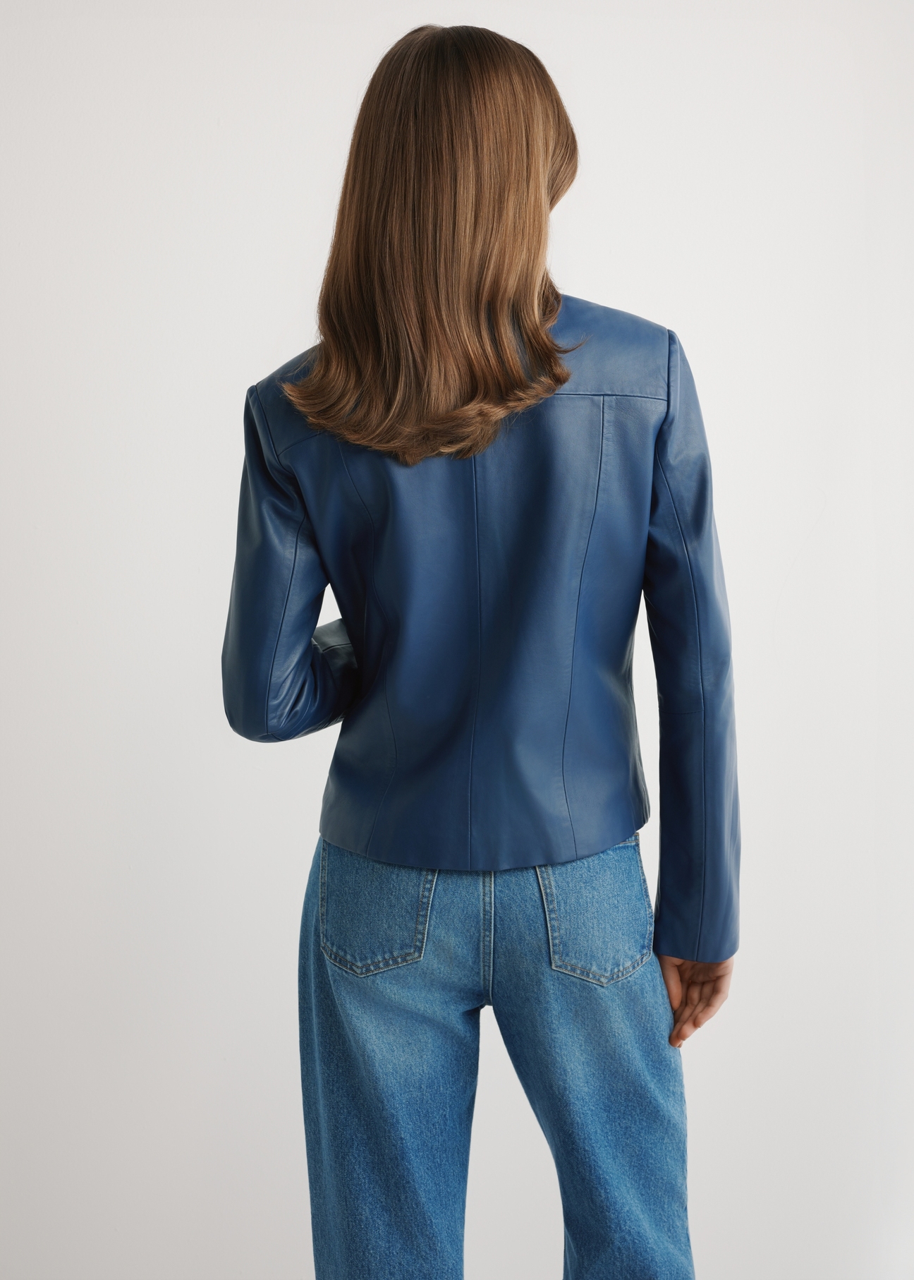 Granatowa skórzana kurtka damska KURDS-0532-7D(W26) - widok produktu z tyłu, na modelce, na jasnym tle. Widoczna połowa sylwetki. 