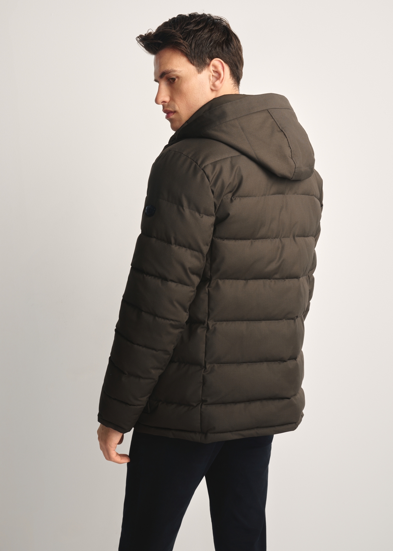 Oliwkowa zimowa kurtka męska KURMT-0379-57(Z25) - widok produktu z tyłu na modelu na białym tle. Widoczna połowa sylwetki.