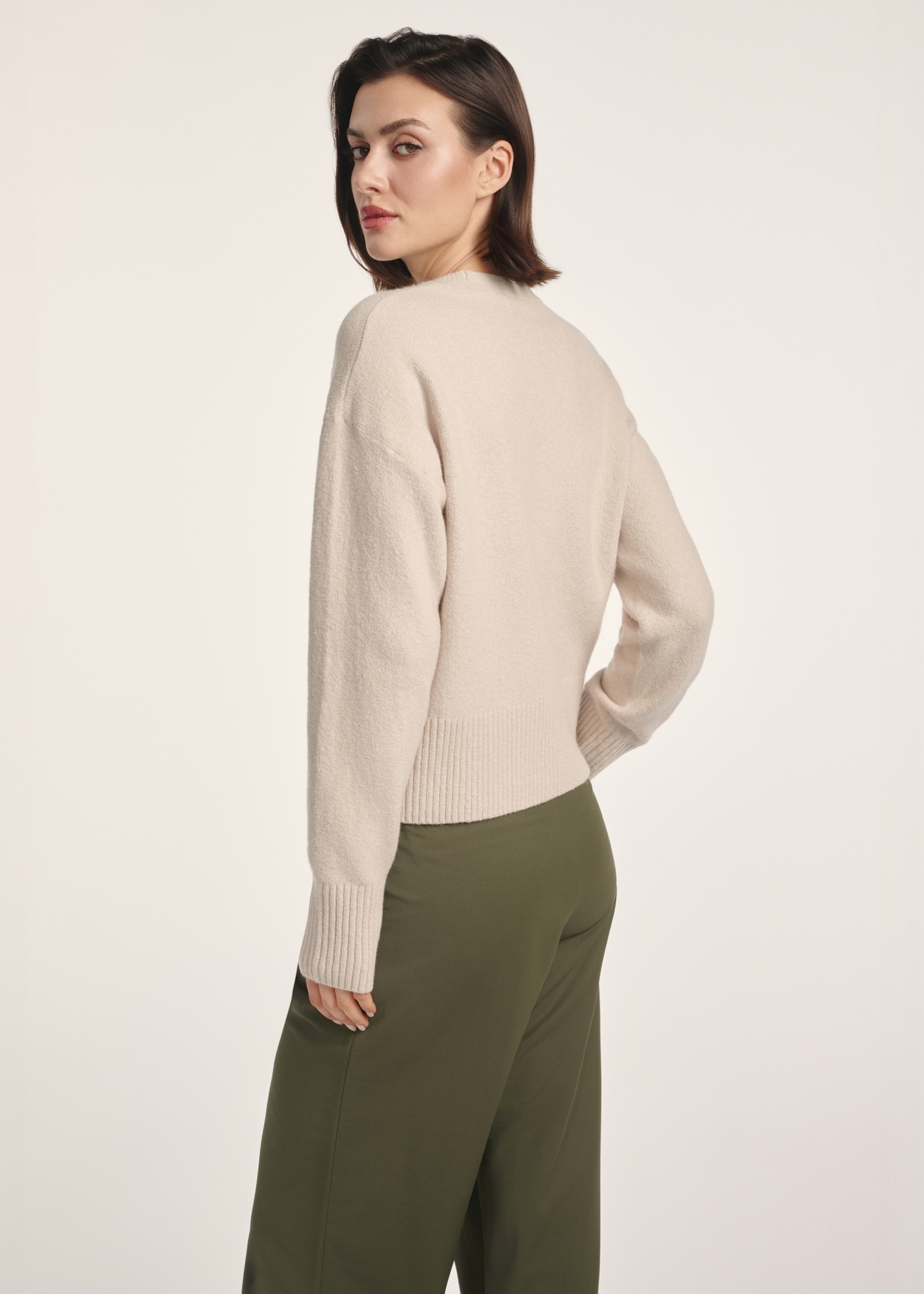 Beżowy sweter damski SWEDT-0242-80(Z25), widok produktu z tyłu na modelce. Widoczna połowa sylwetki.