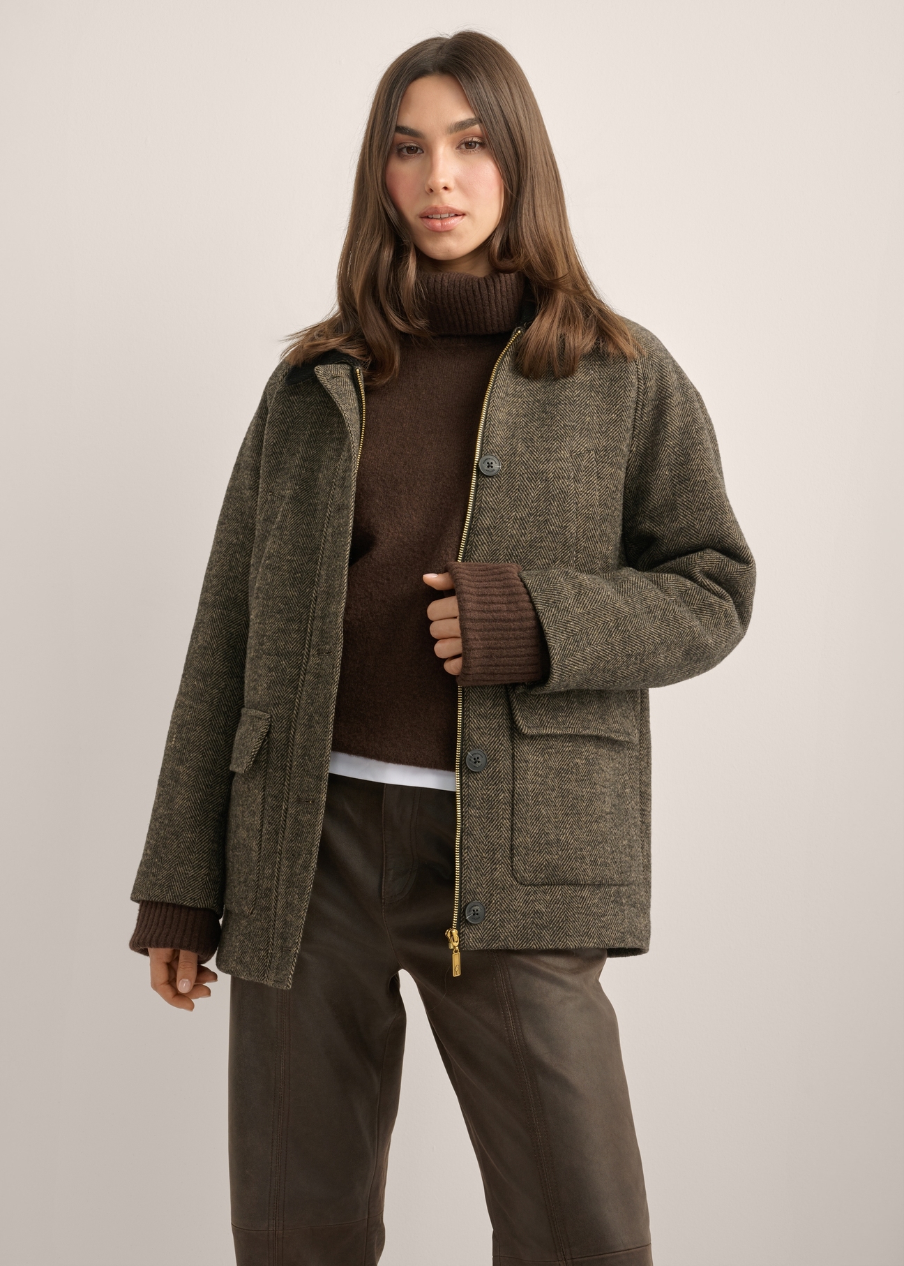 Płaszcz damski w jodełkę PLADT-0083-1L(Z26) - widok produktu z przodu, na modelce, na jasnym tle. Widoczna sylwetka do kolan. 