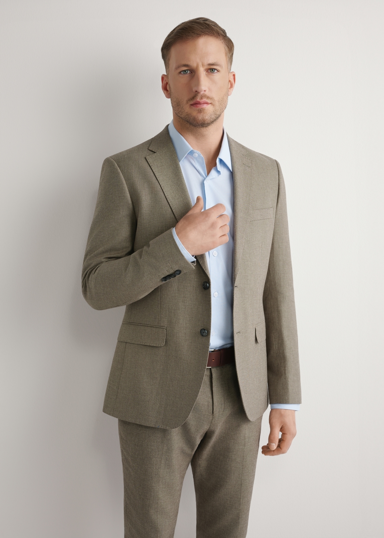 Ciemnobrązowa garniturowa marynarka męska MARMT-0013-1I(W26), widok produktu z przodu na modelu. Widoczna połowa sylwetki.