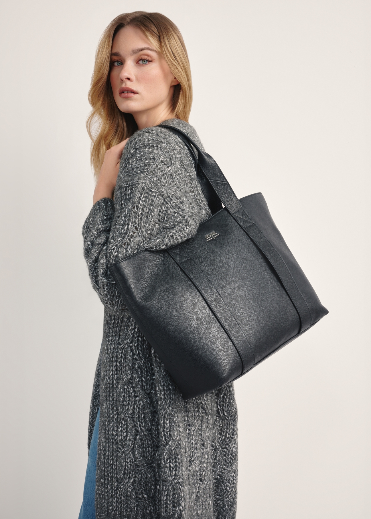 Czarna elegancka shopperka damska TORES-1200-99(Z25), widok produktu na ramieniu modelki na jasnym tle.