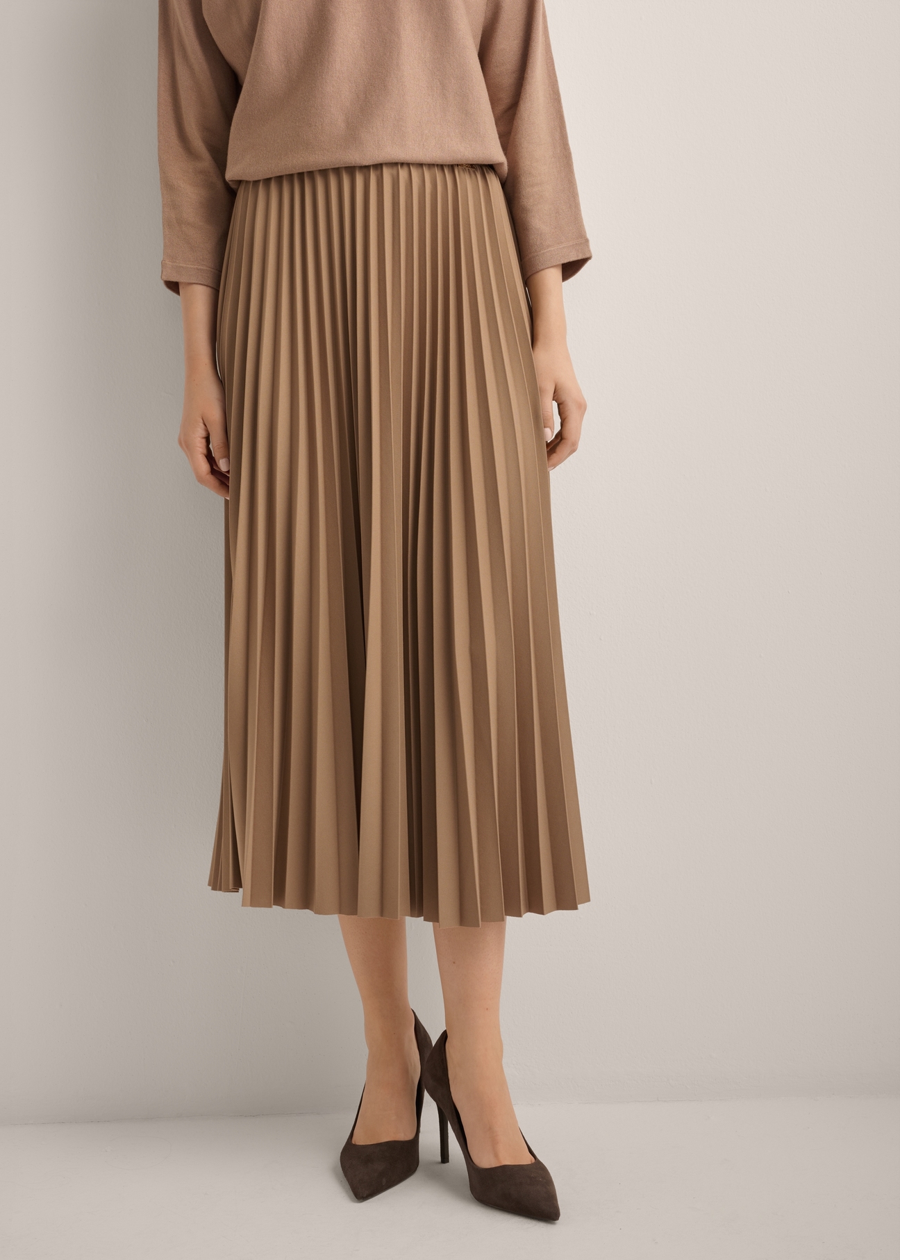 Camelowa plisowana spódnica midi SPCDT-0096-1D(Z26), widok produktu od przodu na modelce. Widoczna połowa sylwetki.