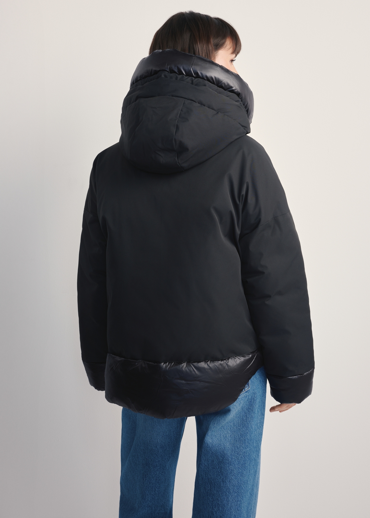 Czarna kurtka damska oversize KURDT-0605-99(Z25), widok produktu z tyłu na modelce. Widoczna połowa sylwetki.