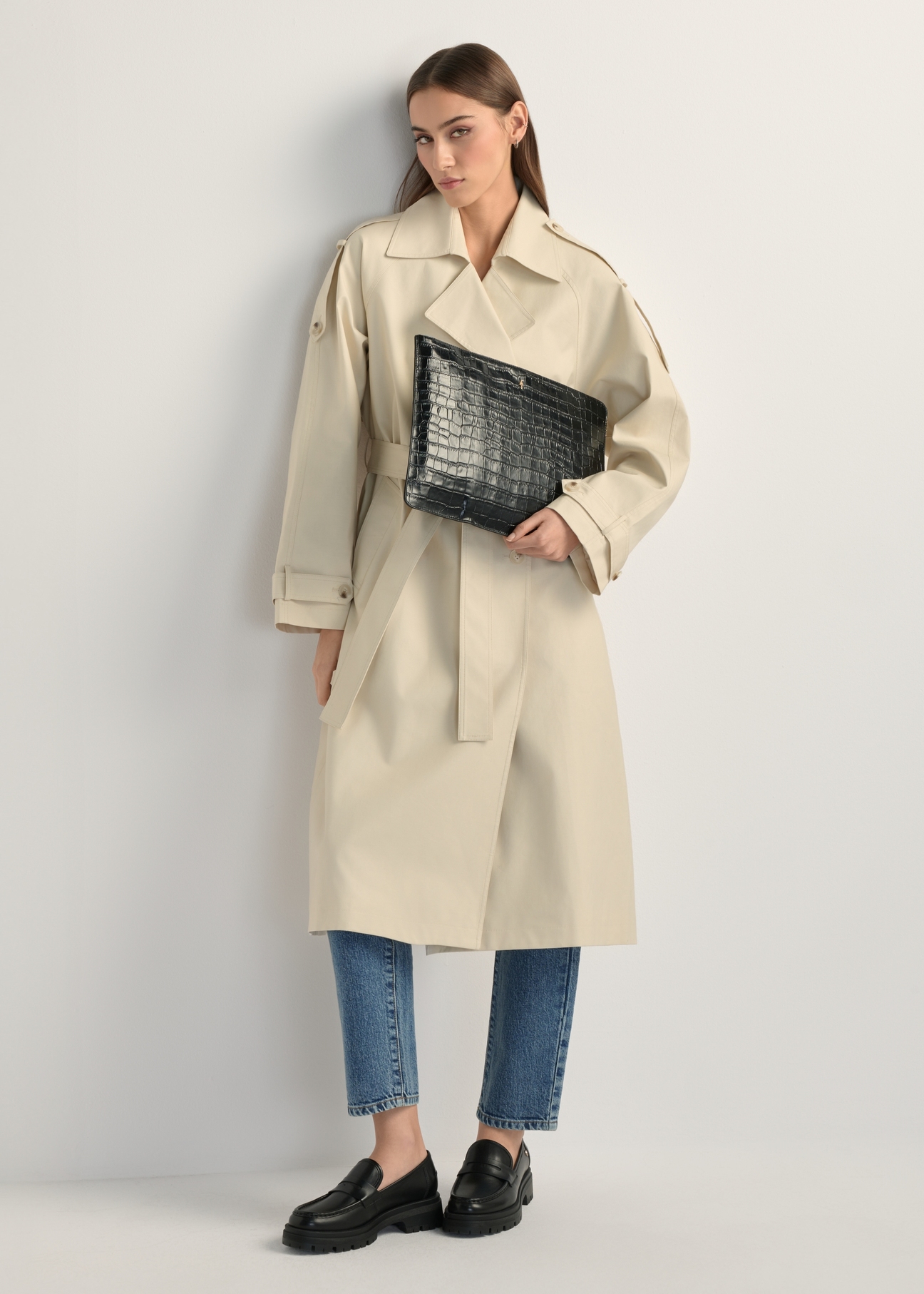 Czarna skórzana teczka damska TORES-0853F-9G(W26) - widok produktu lekko po skosie, na modelce, na jasnym tle. Widoczna cała sylwetka. 