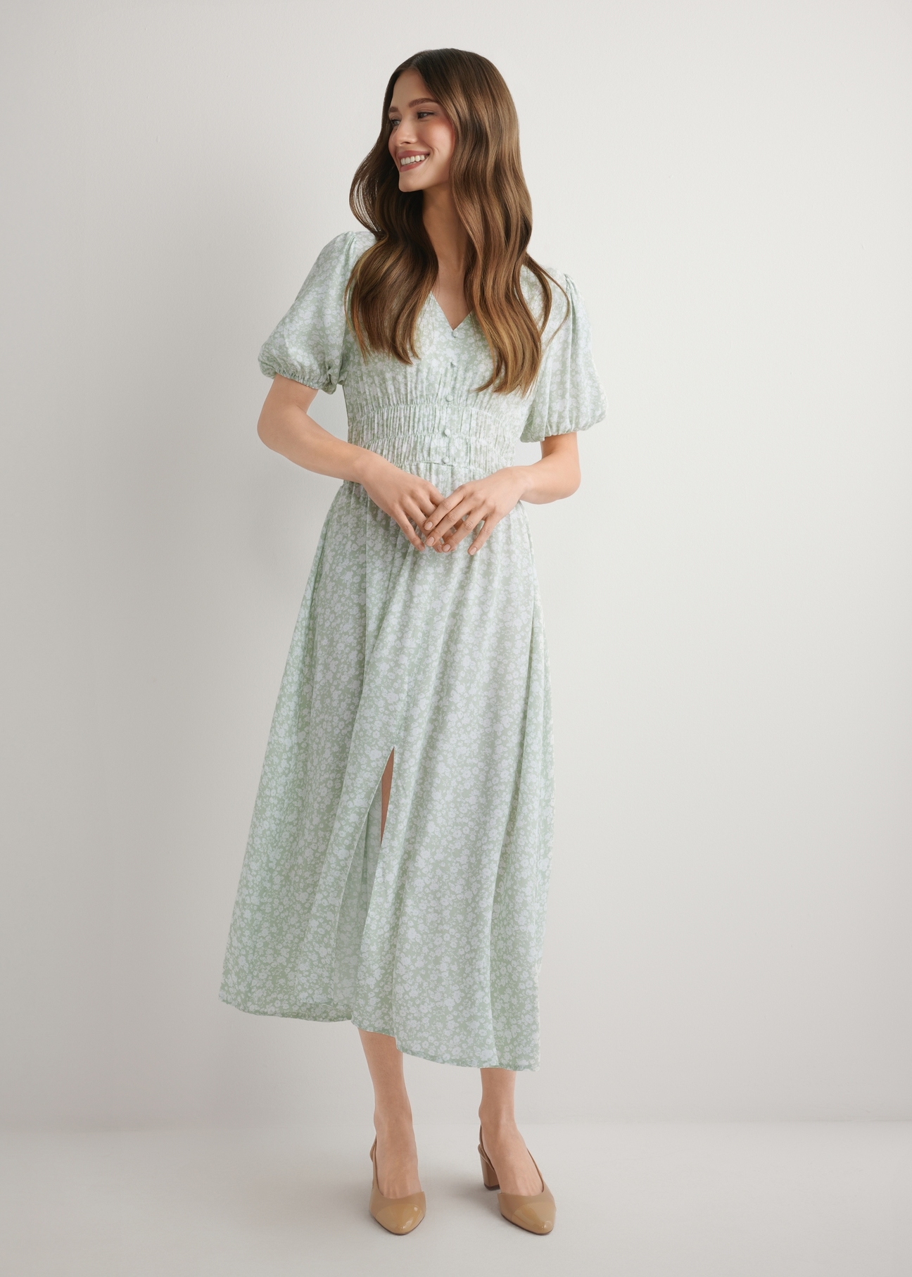 Długa sukienka w kwiaty w kolorze szałwiowym SUKDT-0191-8P(W26), widok produktu z przodu na modelce. Widoczna cała sylwetka.