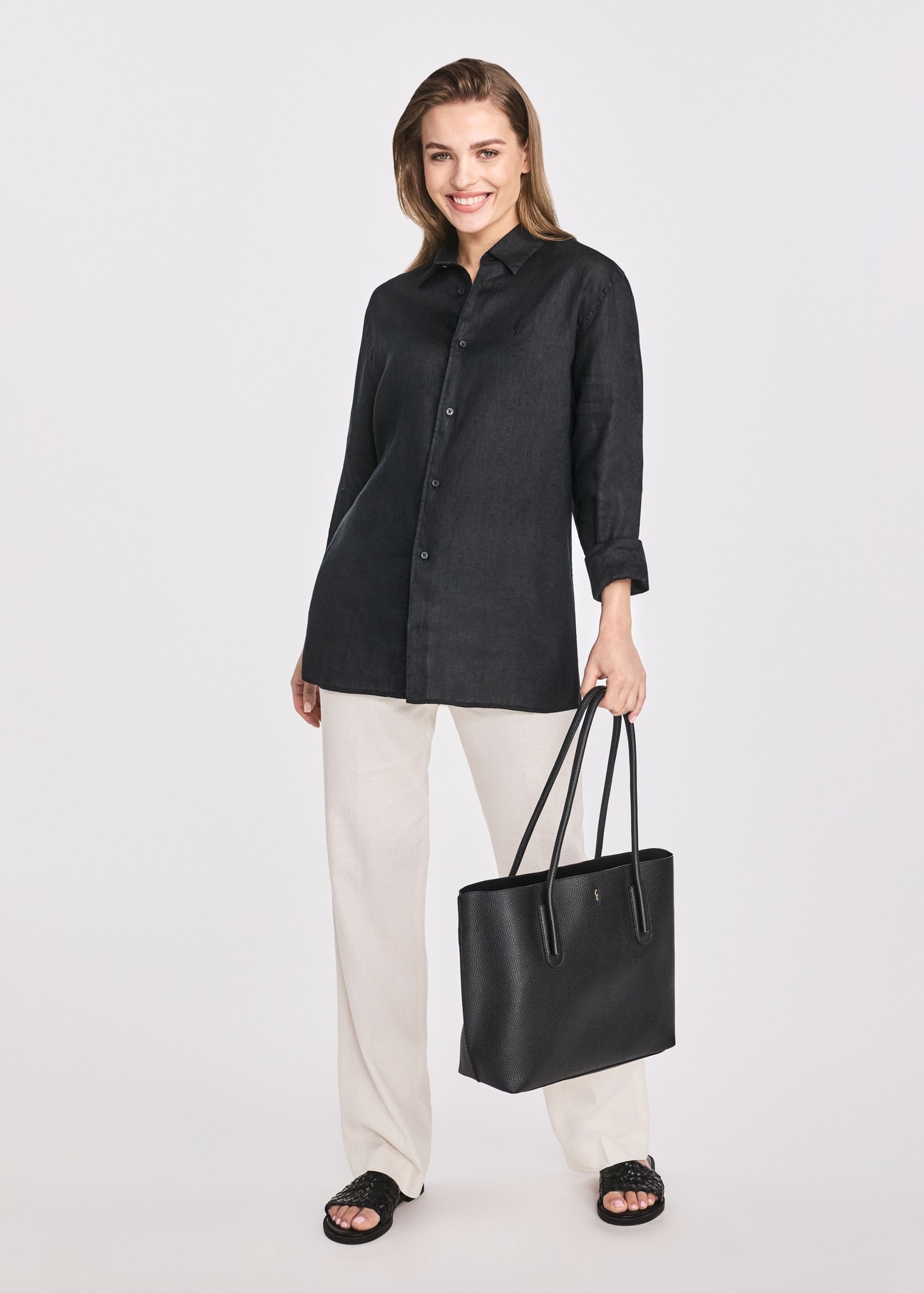 Czarna torebka shopper damska TOREC-0938B-99(Z25), widok produktu w dłoni modelki. Widoczna cała sylwetka.