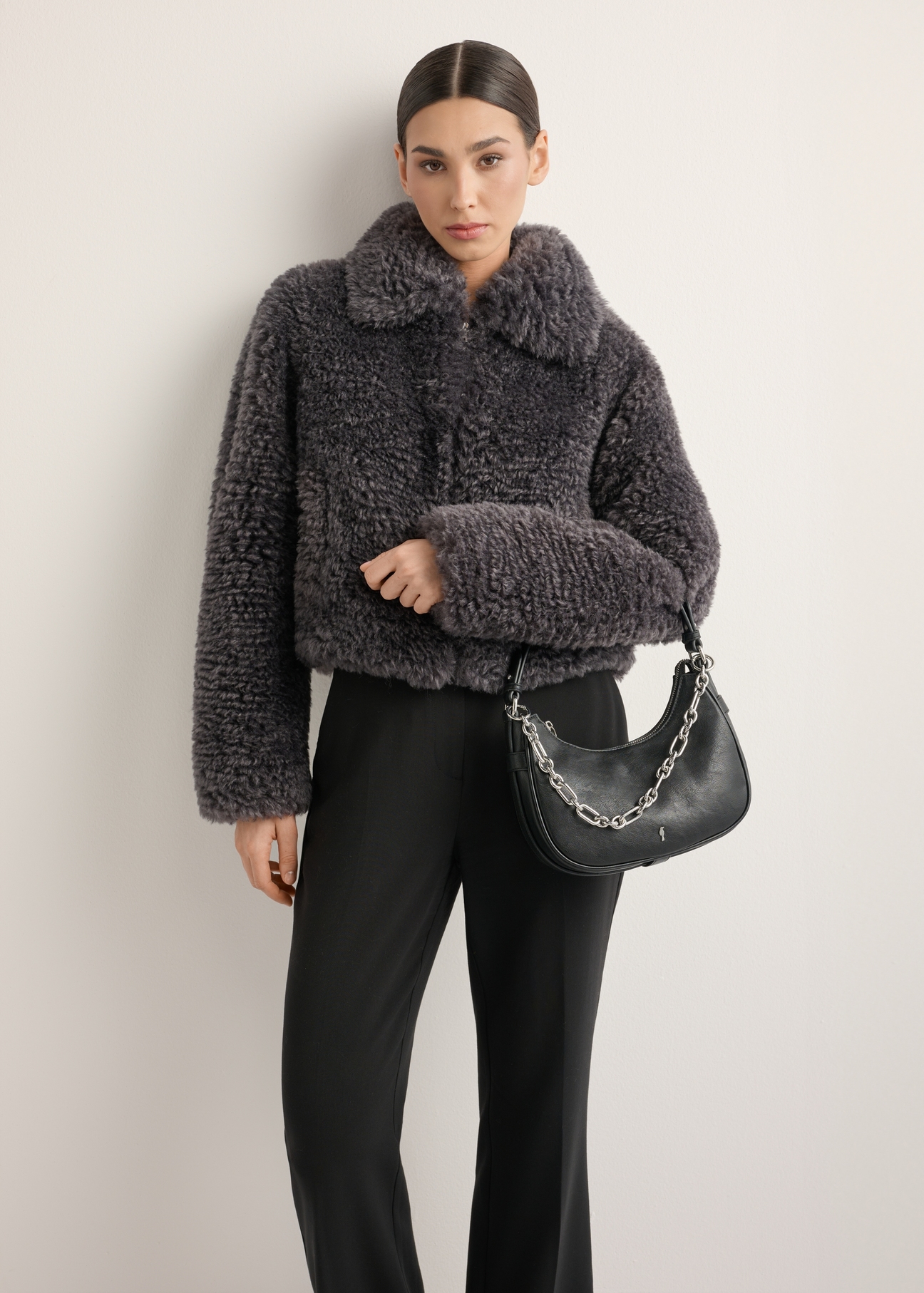 Czarna torebka damska hobo z biżuteryjnym akcentem TOREC-1326-99(Z26), widok skosu produktu na modelce. Widoczna połowa  sylwetki.