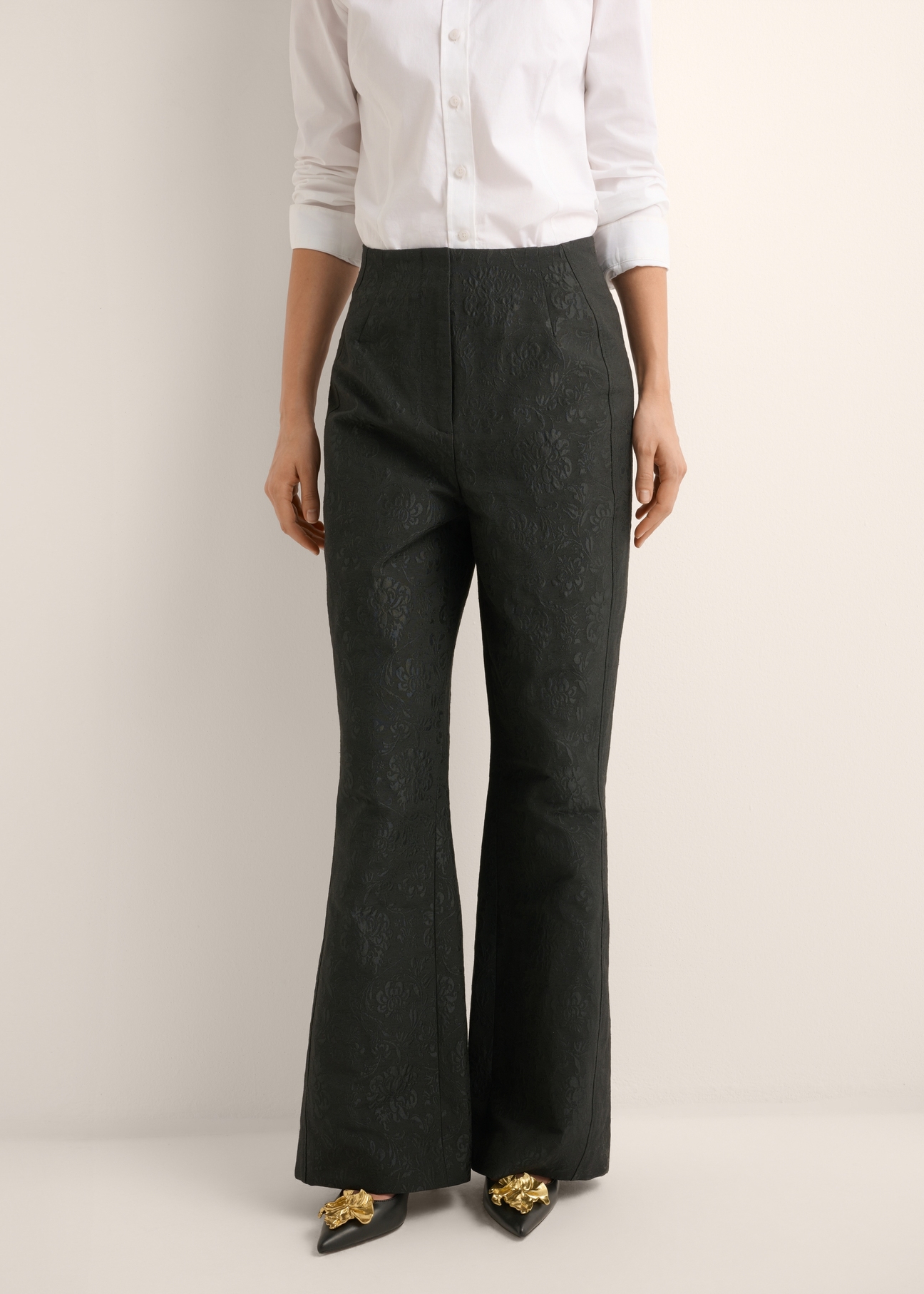Czarne spodnie wide leg w kwiaty SPODT-0127-99(Z26), widok produktu z przodu na modelce. Widoczna połowa sylwetki.