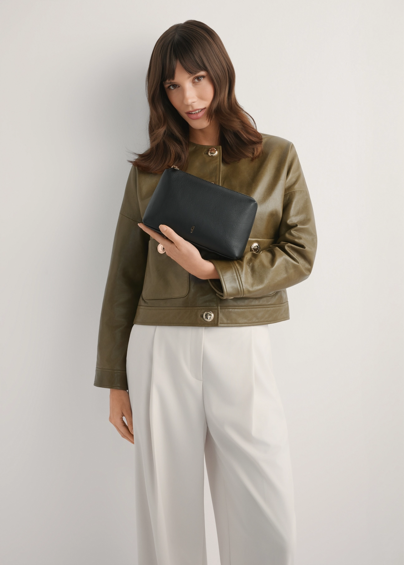 Czarna skórzana kosmetyczka damska TORES-1229-99(W26), widok produktu od przodu na modelce, widoczna połowa sylwetki.