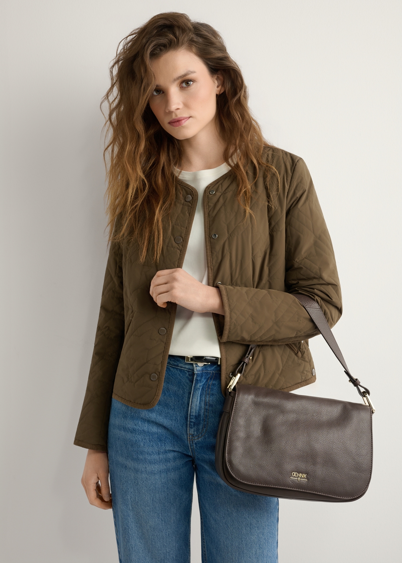 Brązowa skórzana listonoszka damska TORES-1253-1I(W26), widok produktu na ramieniu modelki. Widoczna połowa sylwetki.