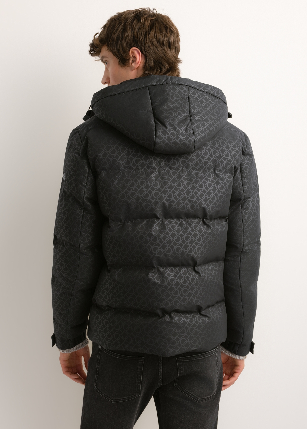 Ciemnoszara kurtka męska w monogram KURMT-0444-9P(Z26), widok produktu z tyłu na modelu. Widoczna połowa sylwetki.
