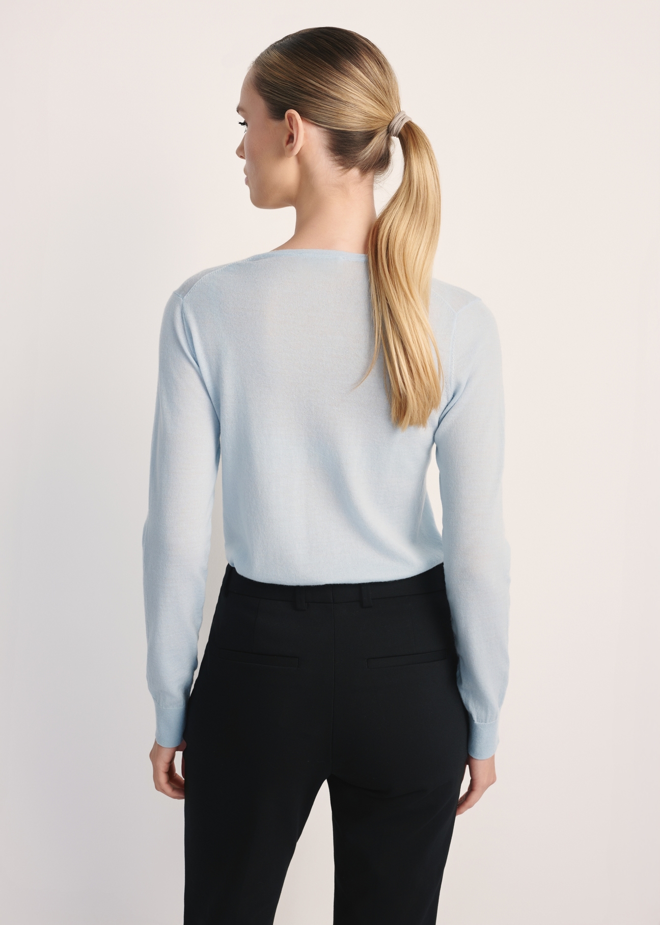 Błękitny sweter damski SWEDT-0250-62(Z25), widok produktu z tyłu na modelce. Widoczna połowa sylwetki.