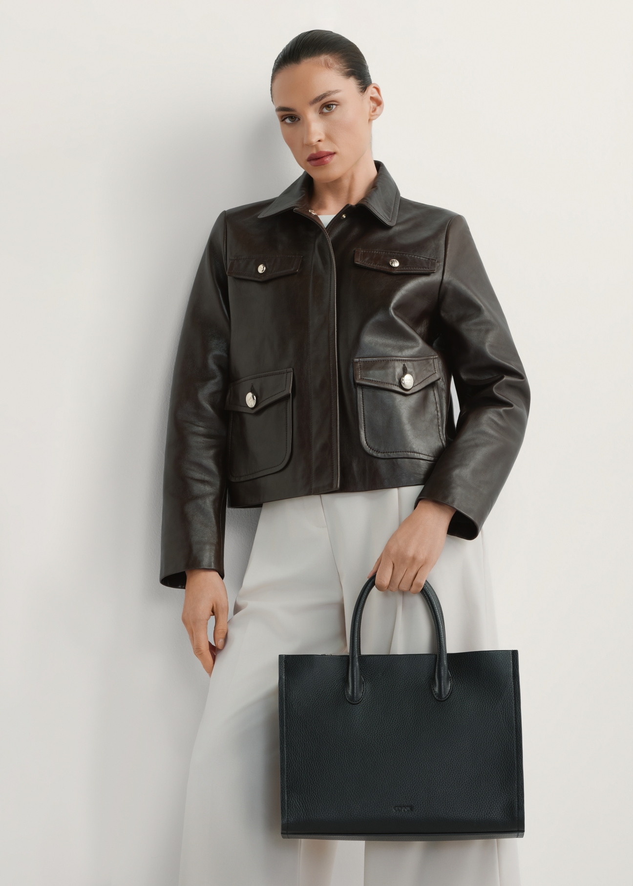 Skórzana torebka damska w kolorze czarnym TORES-1206-9I(W26), widok produktu w dłoni modelki. Widoczna połowa sylwetki.