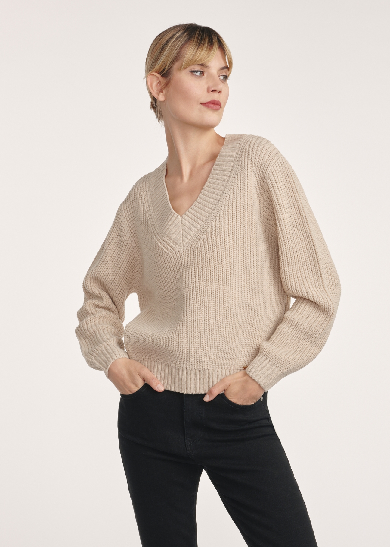 Beżowy sweter dekolt V damski SWEDT-0162-80(Z25), produkt widoczny z przodu na modelce, widoczne pół sylwetki.