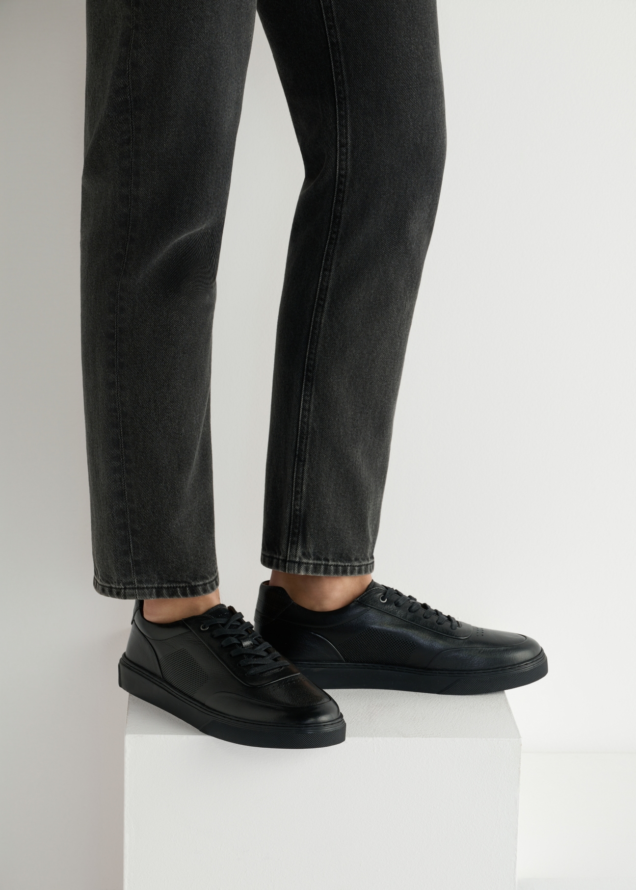 Czarne skórzane sportowe buty męskie BUTYM-0484-99(W25), widok produktu od boku na modelu, widoczna połowa sylwetki.