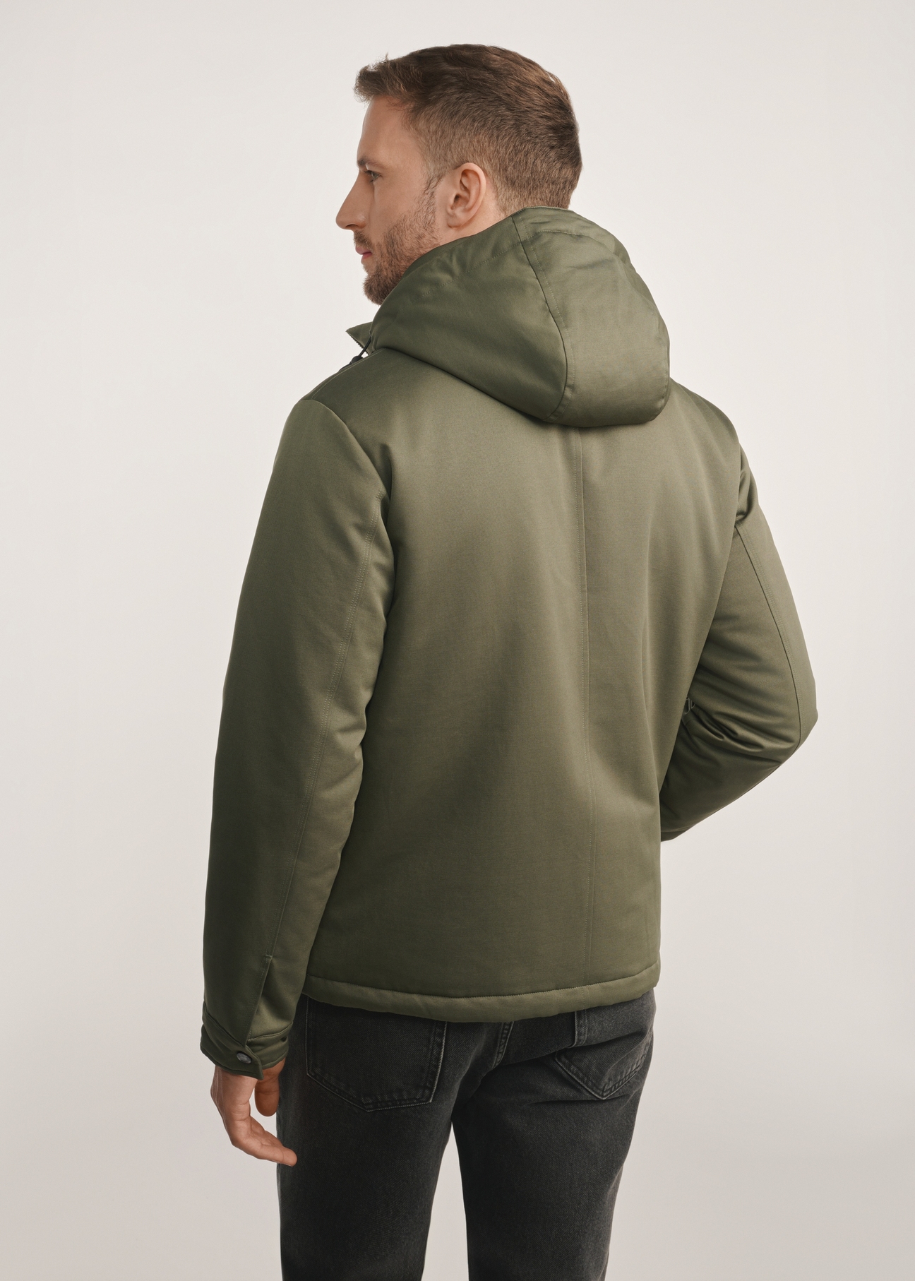 Kurtka męska w kolorze khaki KURMT-0386-54(Z25) - widok produktu z tyłu na modelu na białym tle. Widoczna sylwetka do kolan. 
