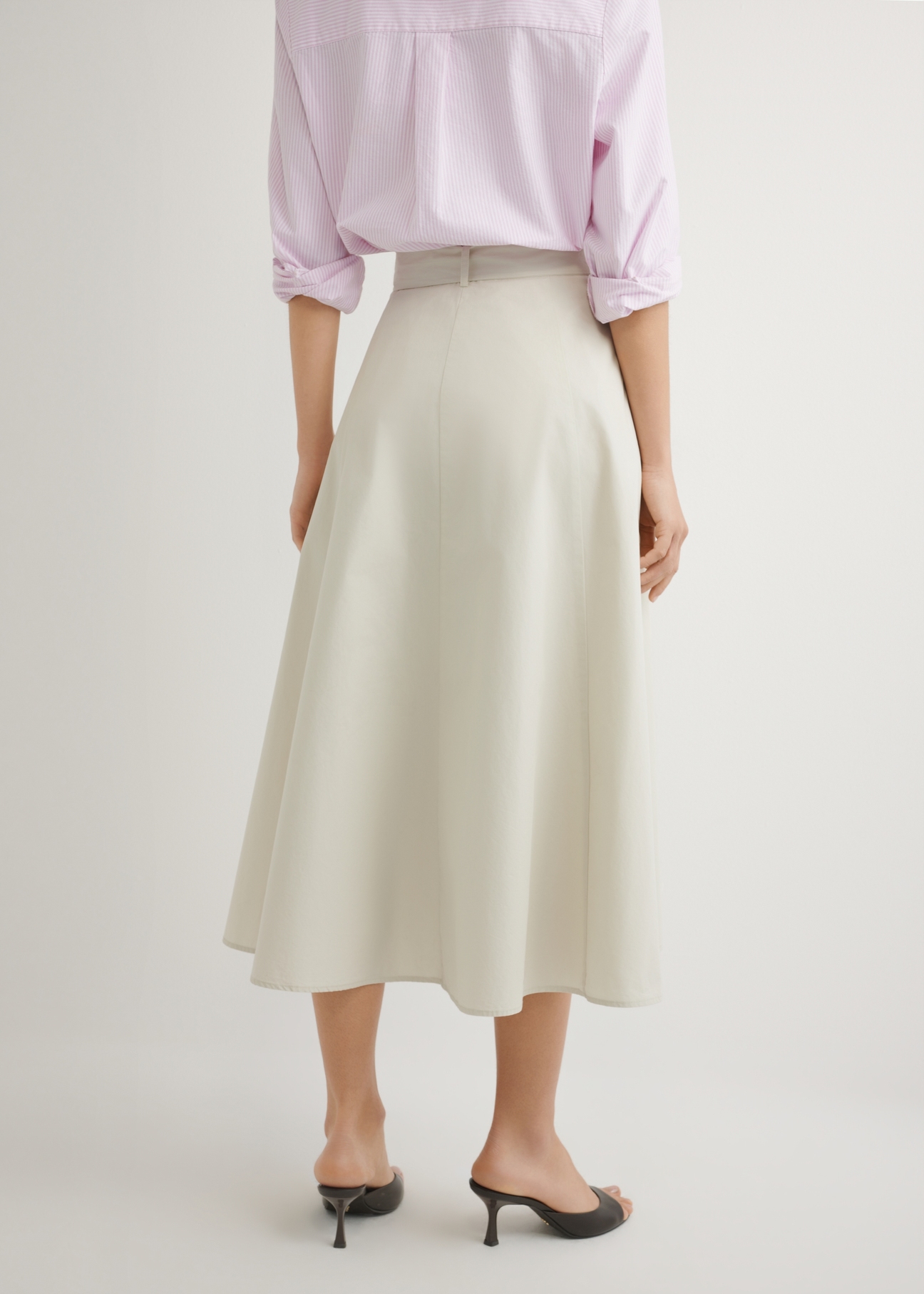 Beżowa spódnica midi SPCDT-0123-1A(W26), widok produktu z tyłu na modelce. Widoczna połowa sylwetki.