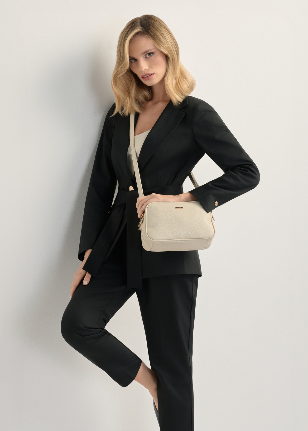 Kremowa średnia torebka damska TOREC-1121-0B(W26), widok produktu na ramieniu modelki. Widoczna połowa sylwetki.