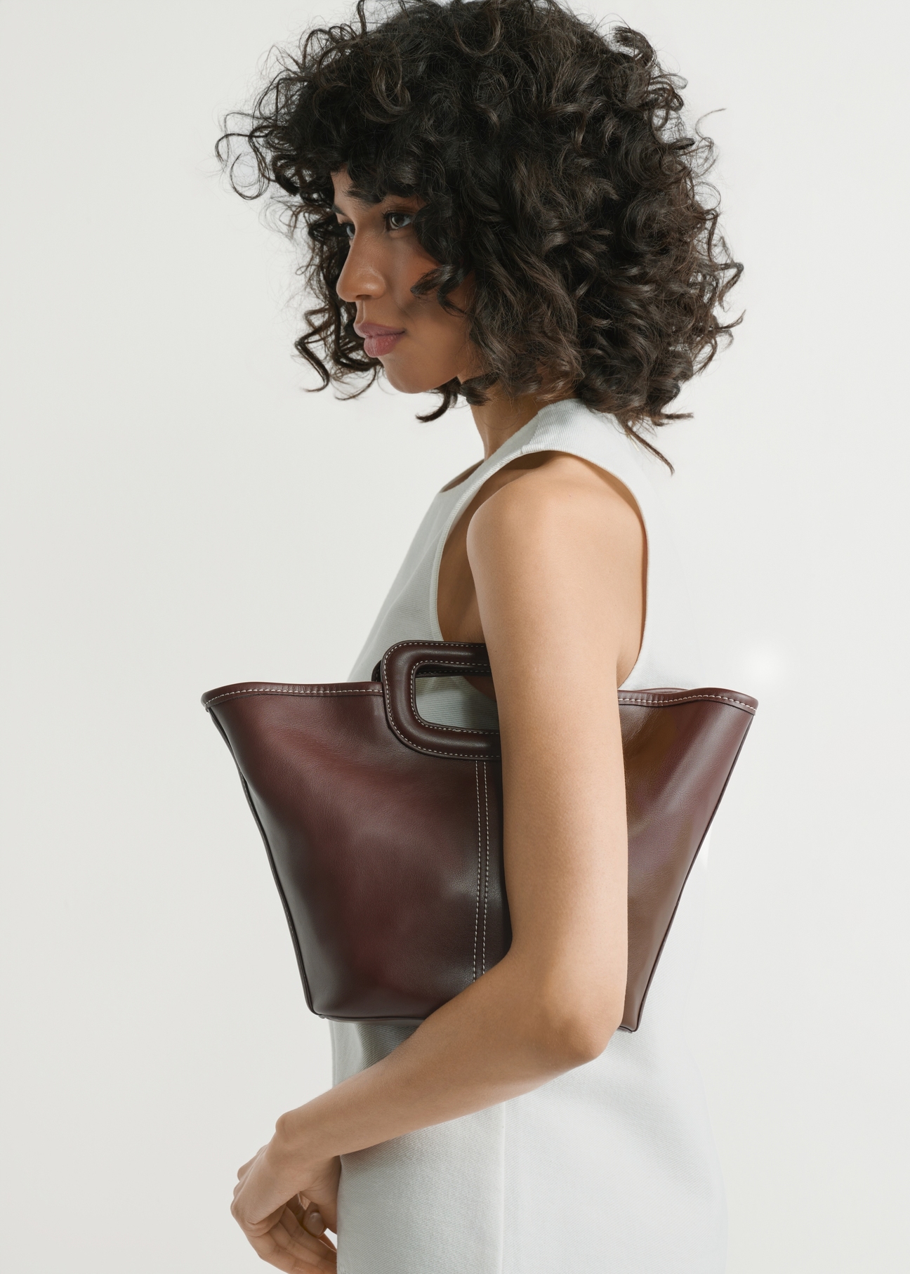 Ciemnobrązowa damska torebka z przeszyciami TOREC-1213-1H(W26), widok produktu w rękach modelki. Widoczna połowa sylwetki.
